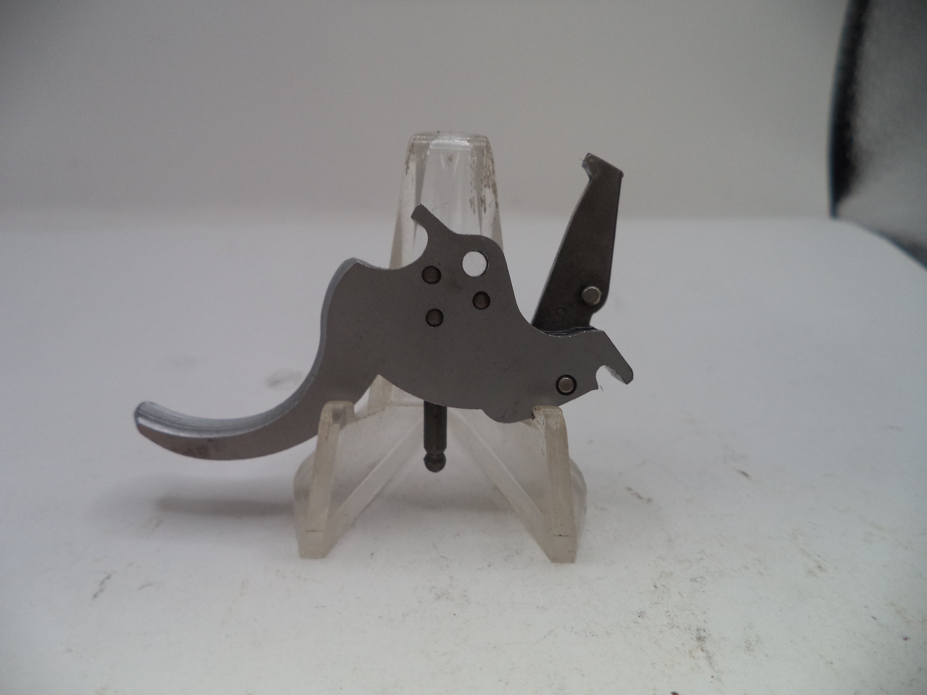 Metallic object on a stand against a plain background