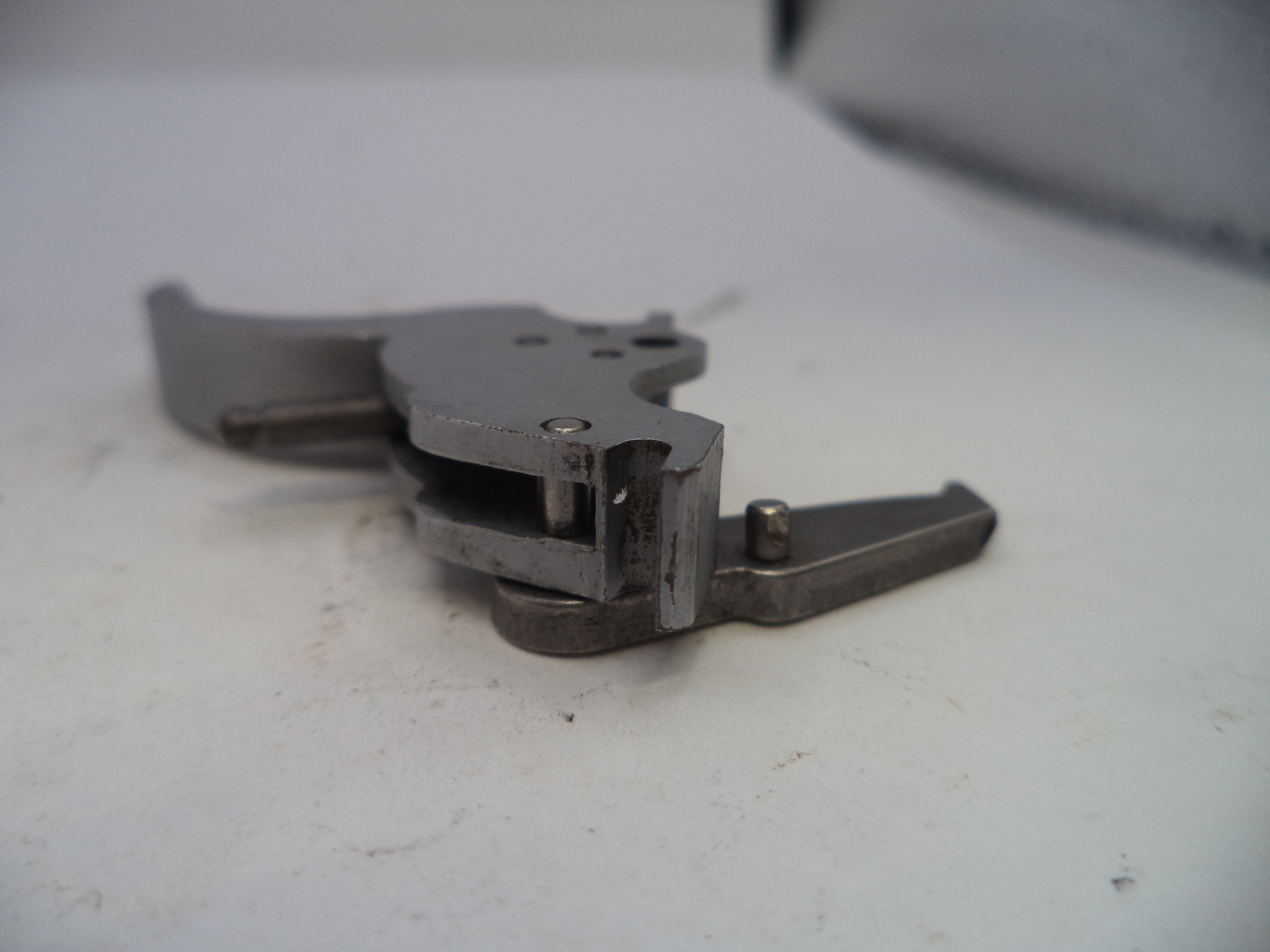 Metallic firearm part on a white surface