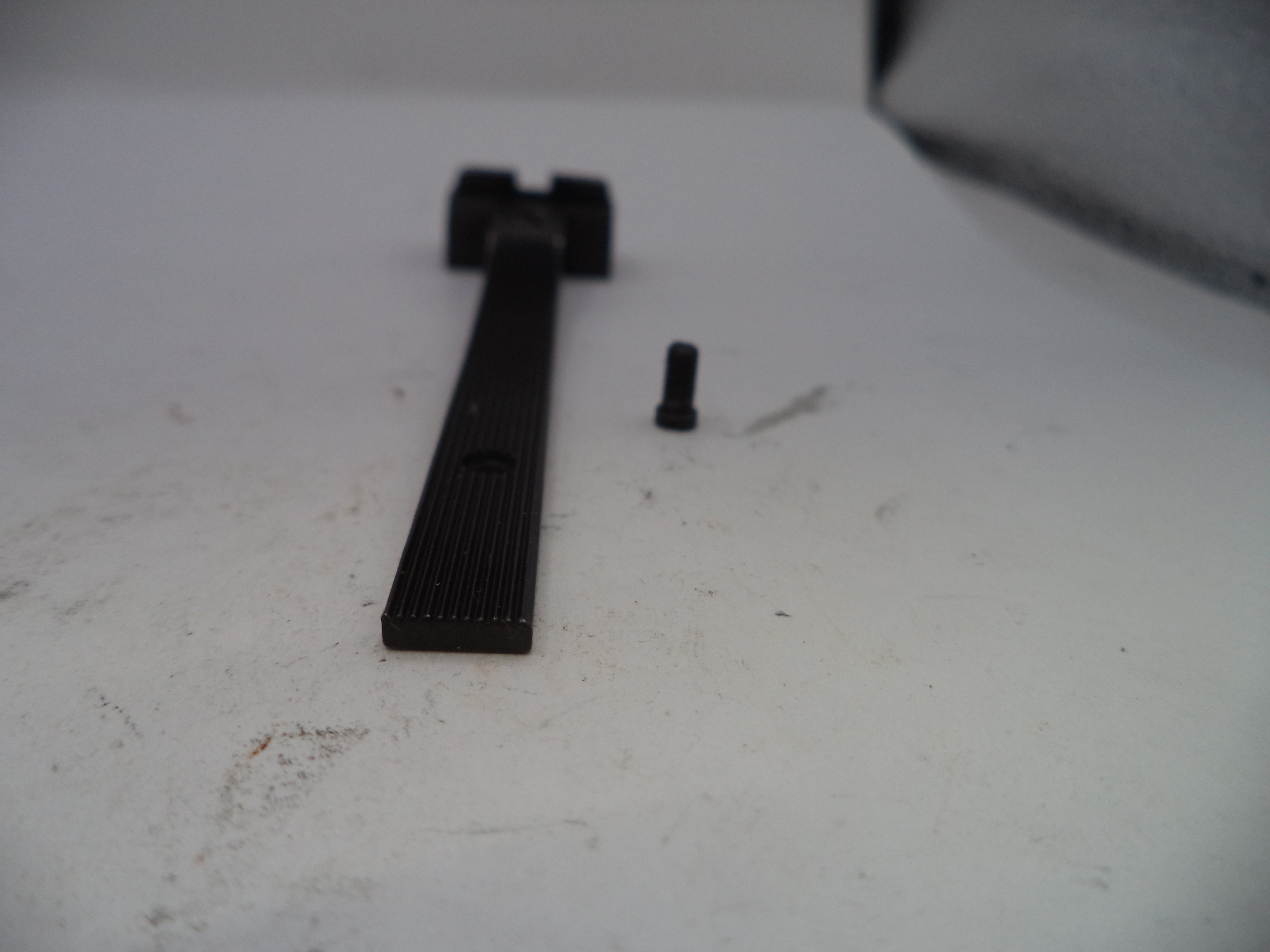 Black metal rod and small black object on a white surface