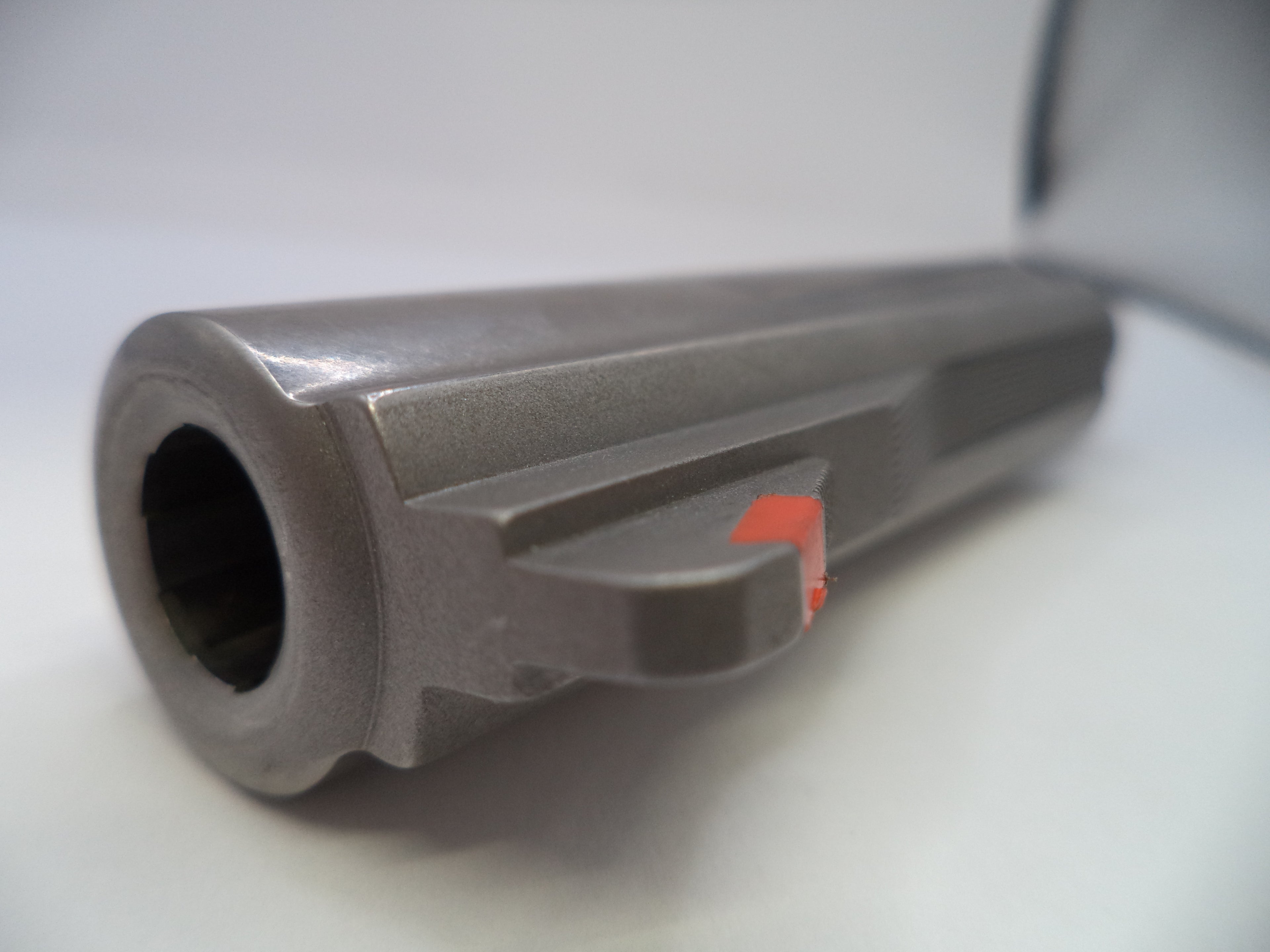 Close-up of a metallic cylindrical object with a red label on a white background