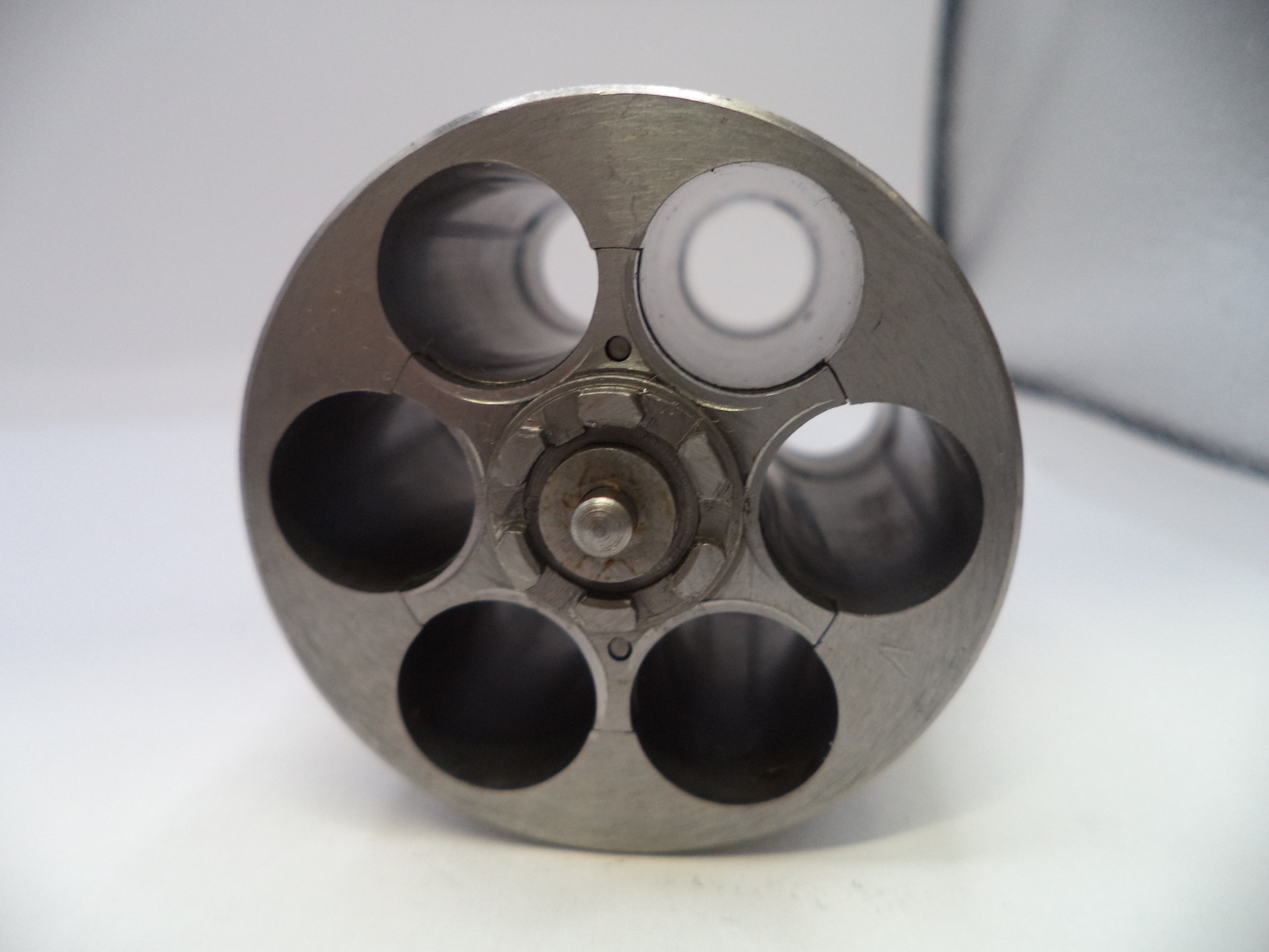 Metallic cylindrical object with multiple chambers on a white background