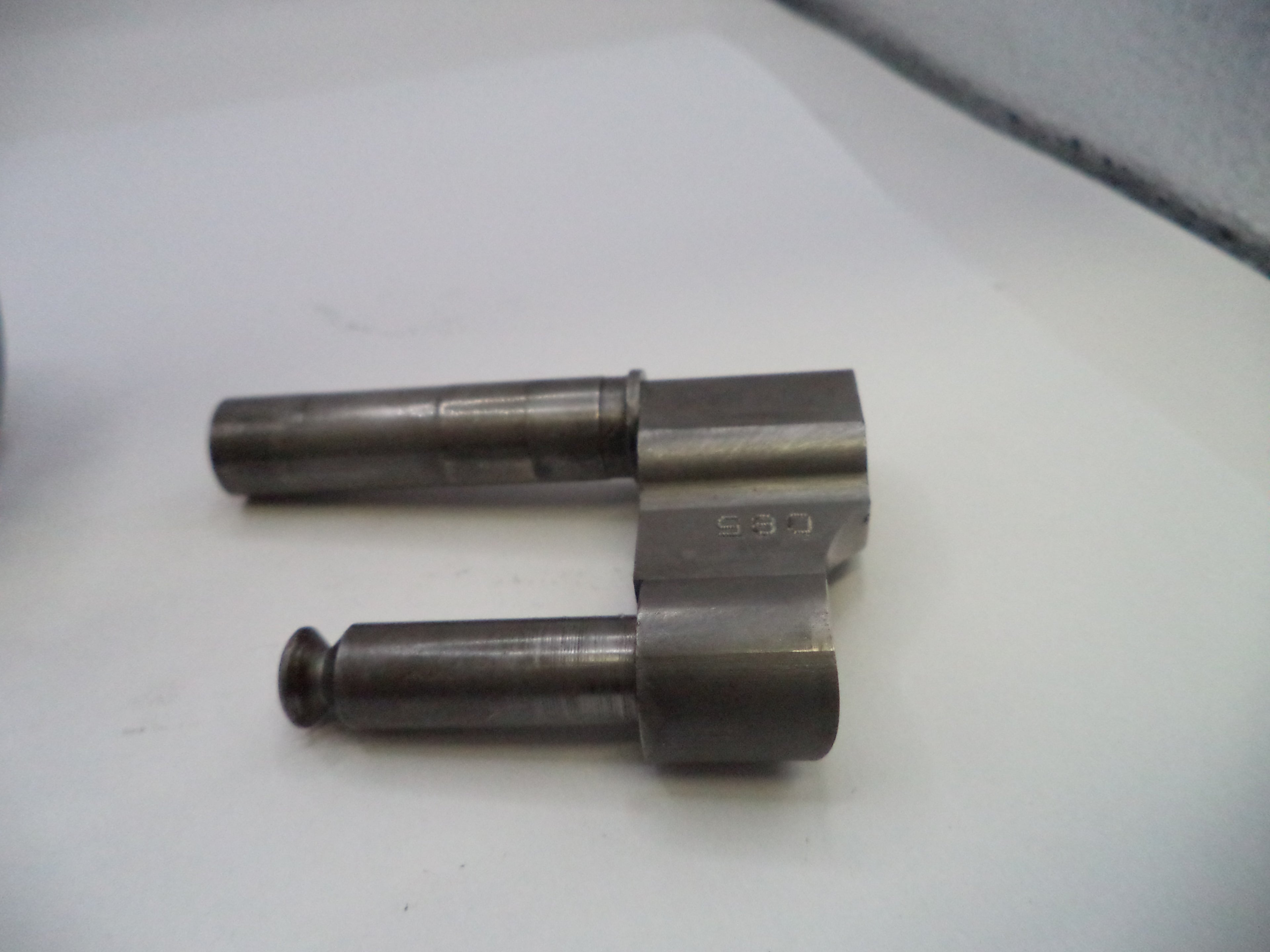 Two metal cylindrical components on a white surface