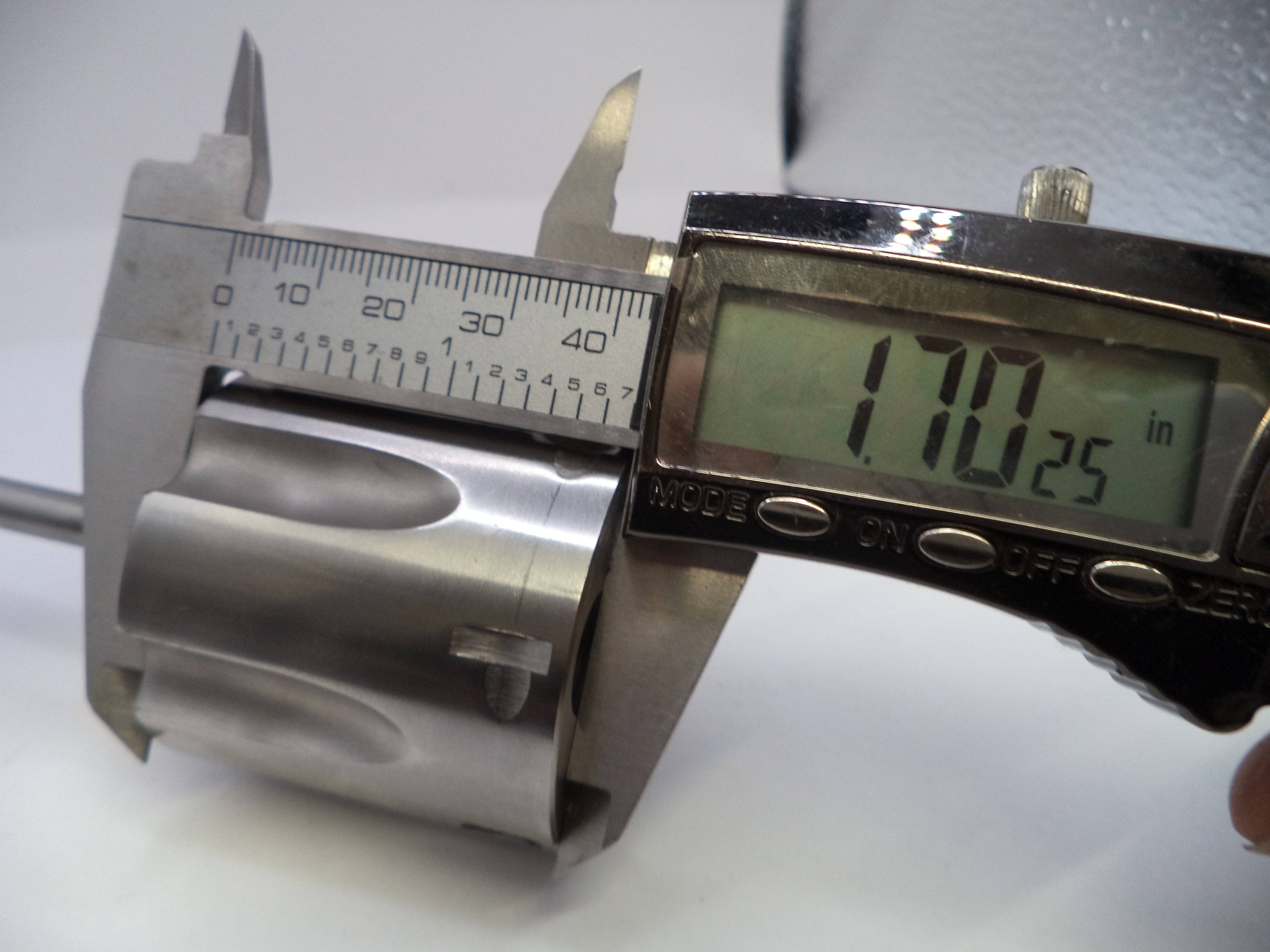 Digital caliper measuring a metal cylindrical object on a white background