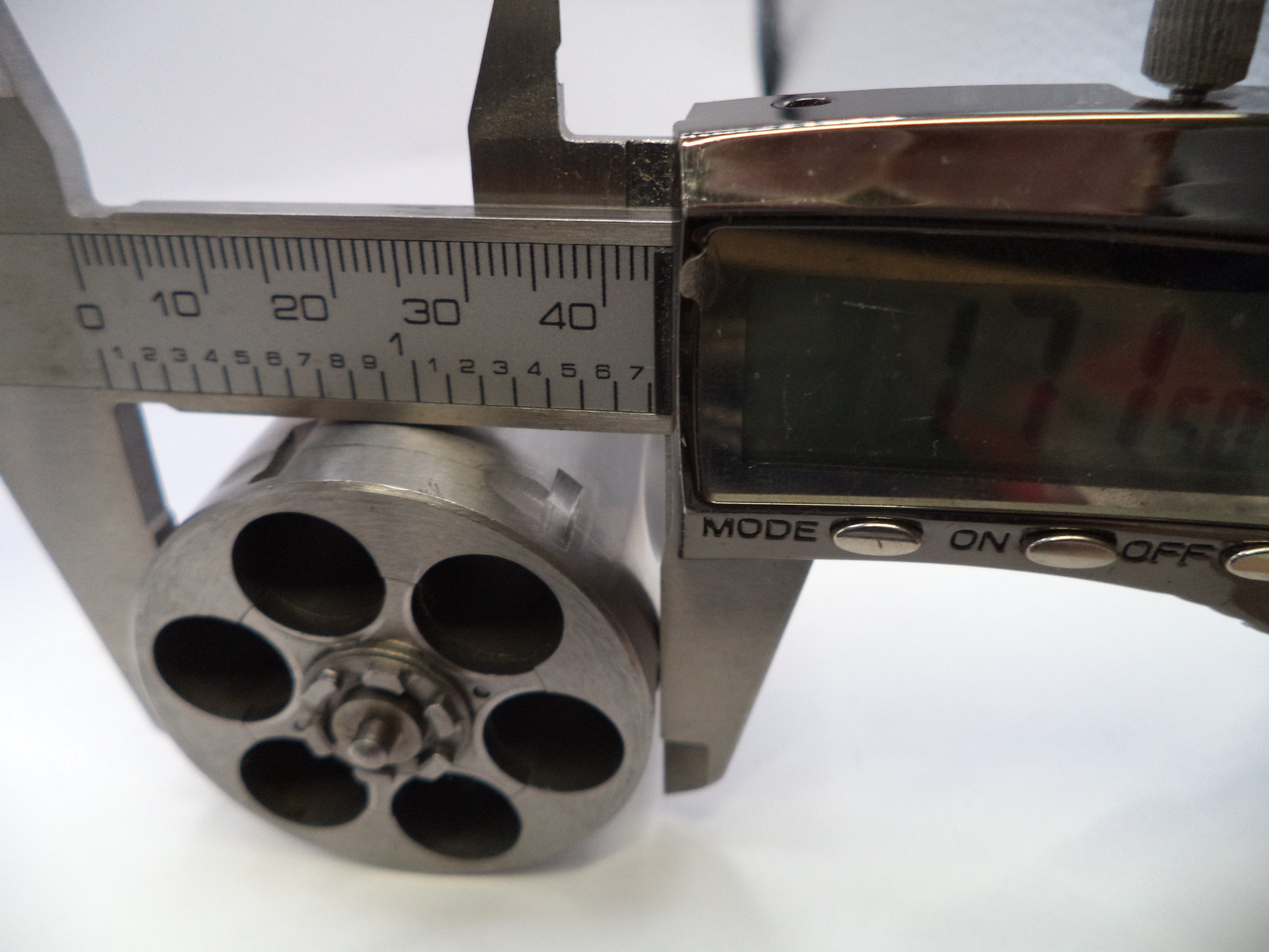 Caliper measuring a cylindrical metal object with a digital display on a white background