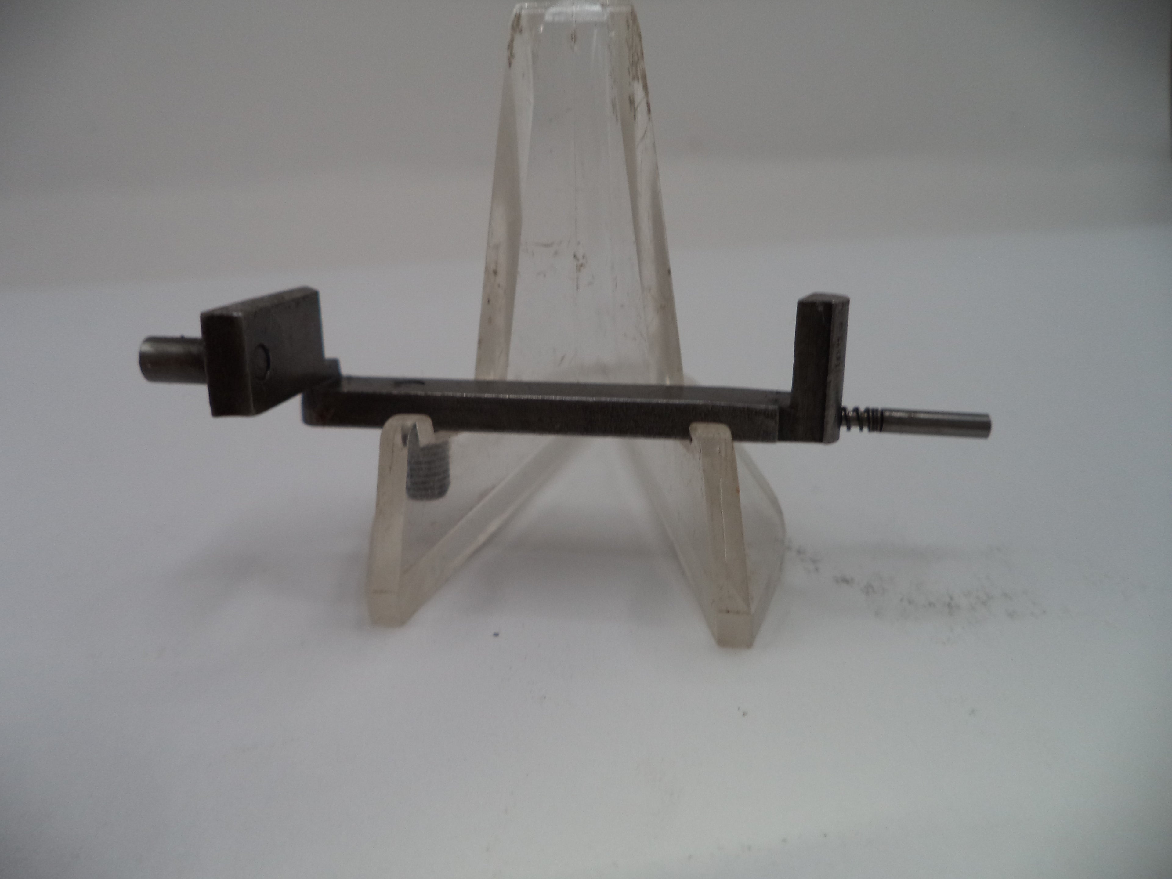 Metal tool on a clear stand against a white background