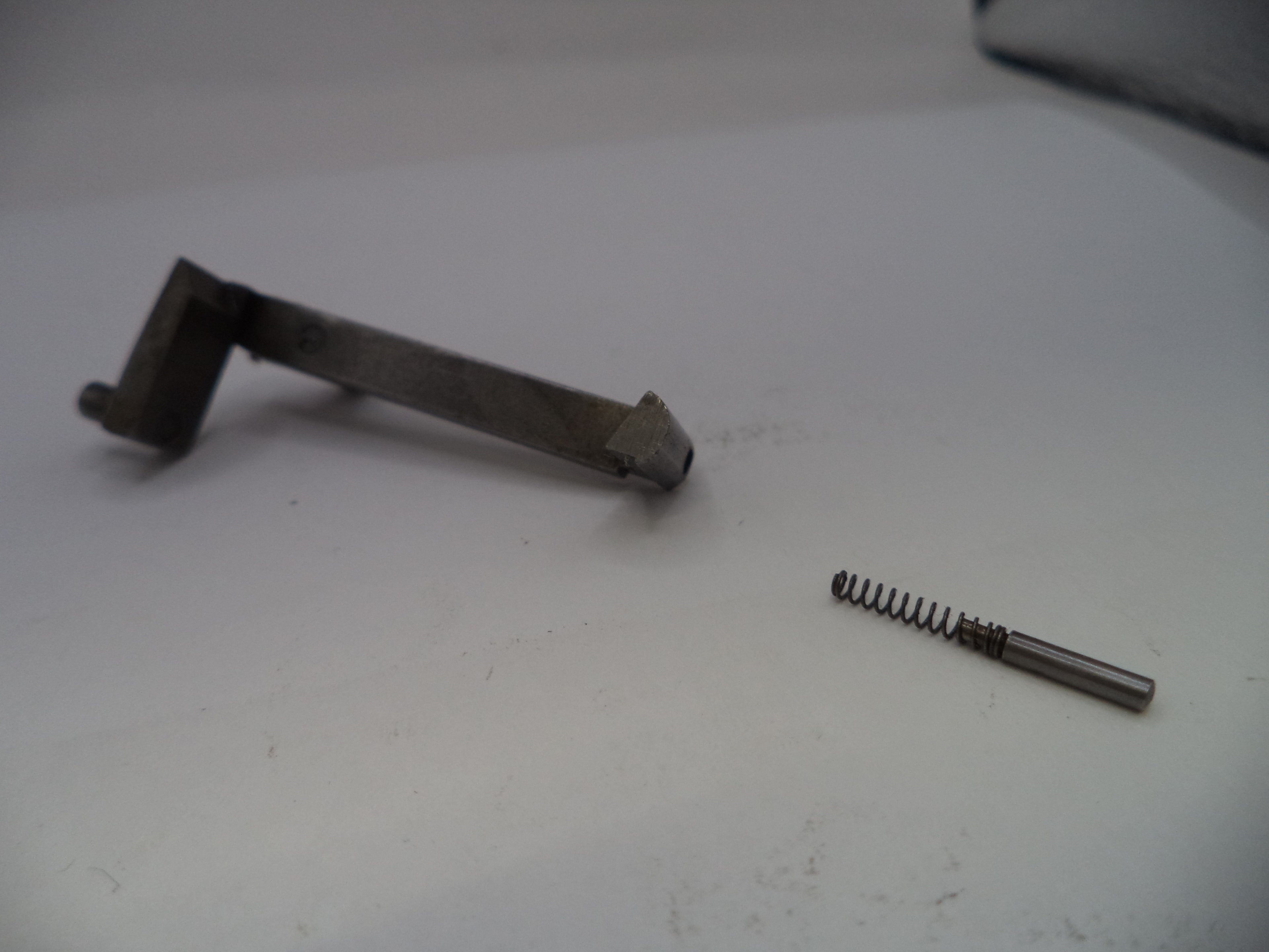 Metal gun part and spring on a white surface