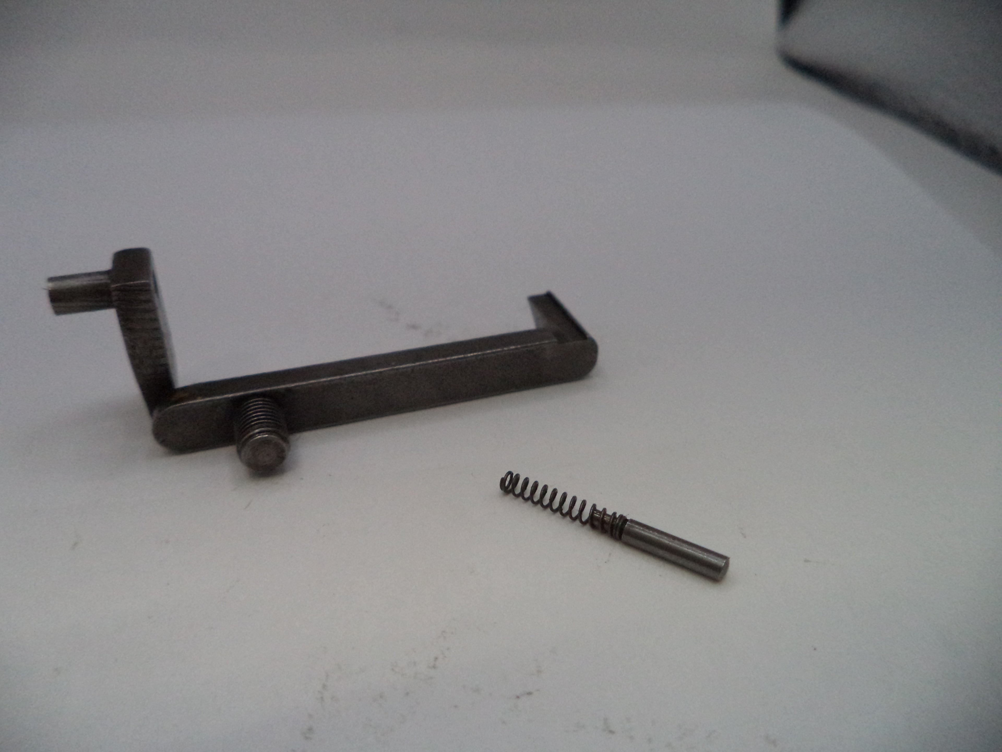 Metal tool and spring on a white surface