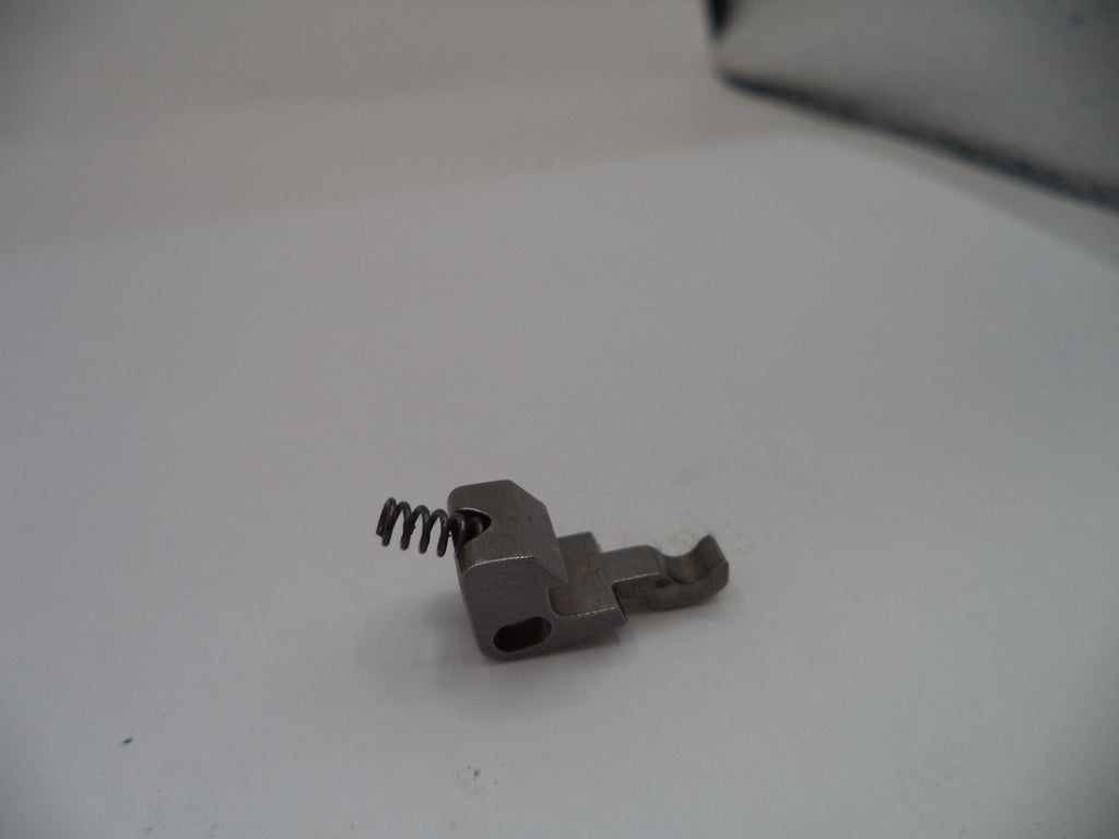 Small metal component with a spring on a white surface