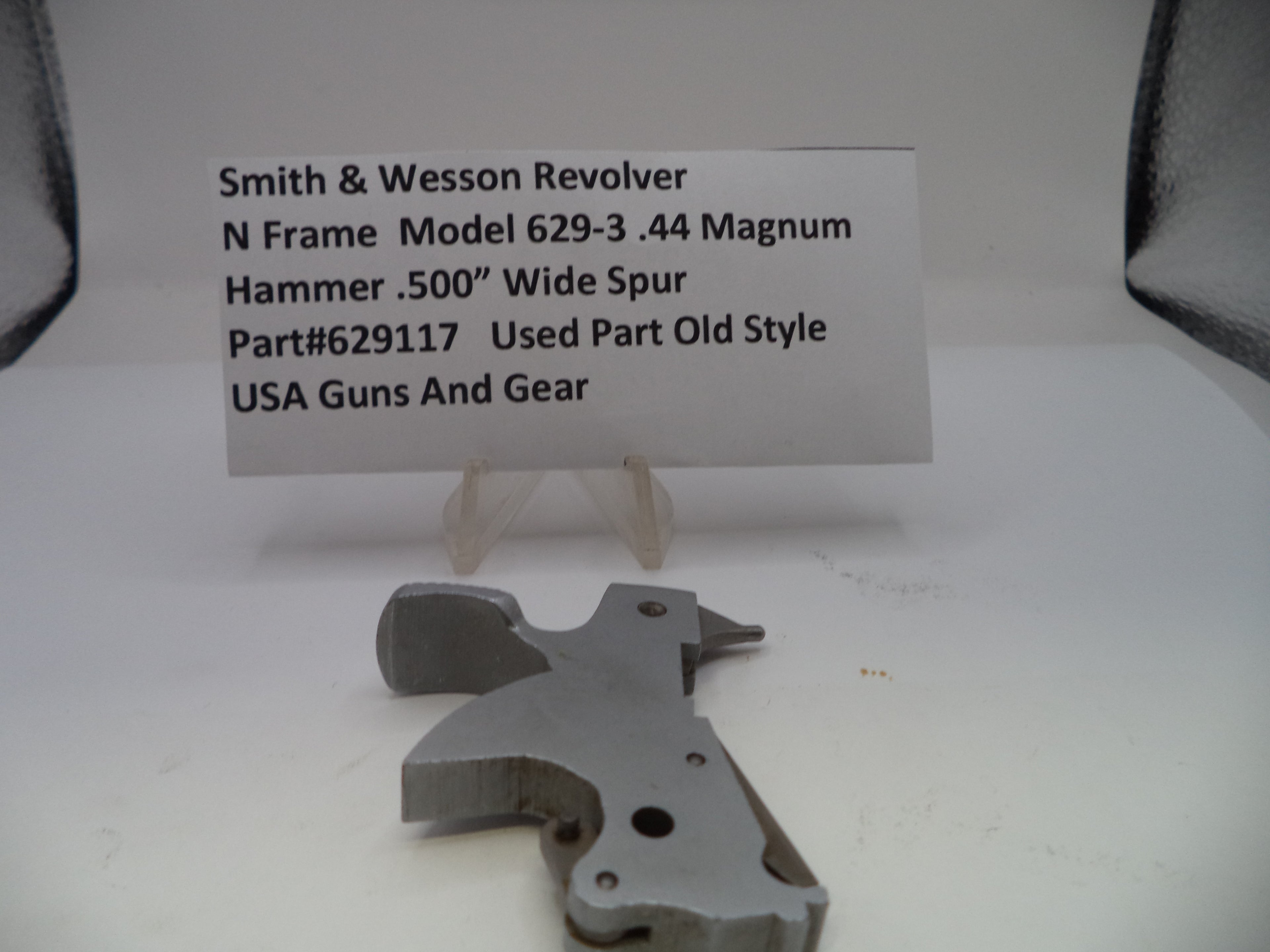 Metal gun part with descriptive card on a white background