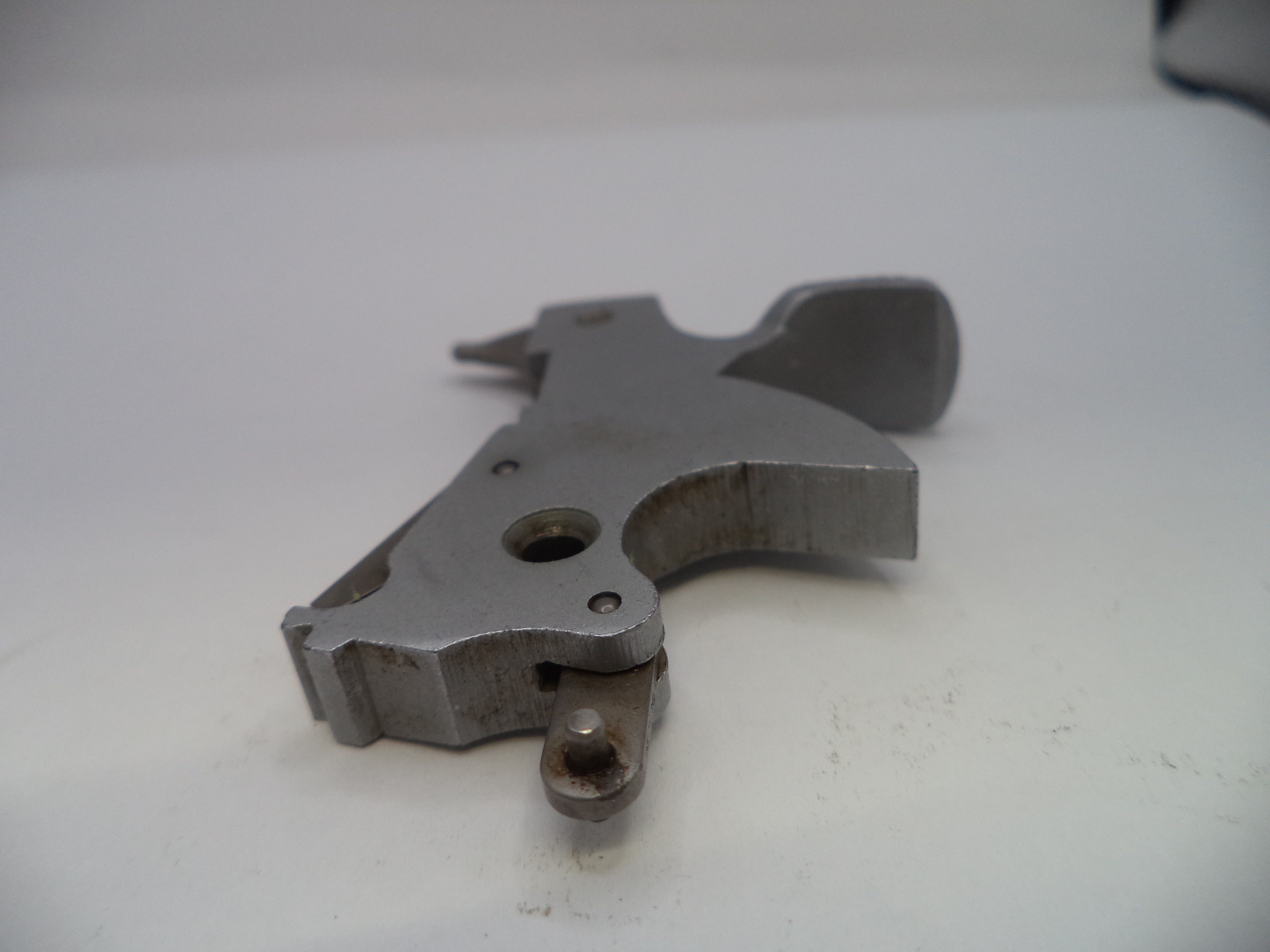 Metallic firearm part on a white surface