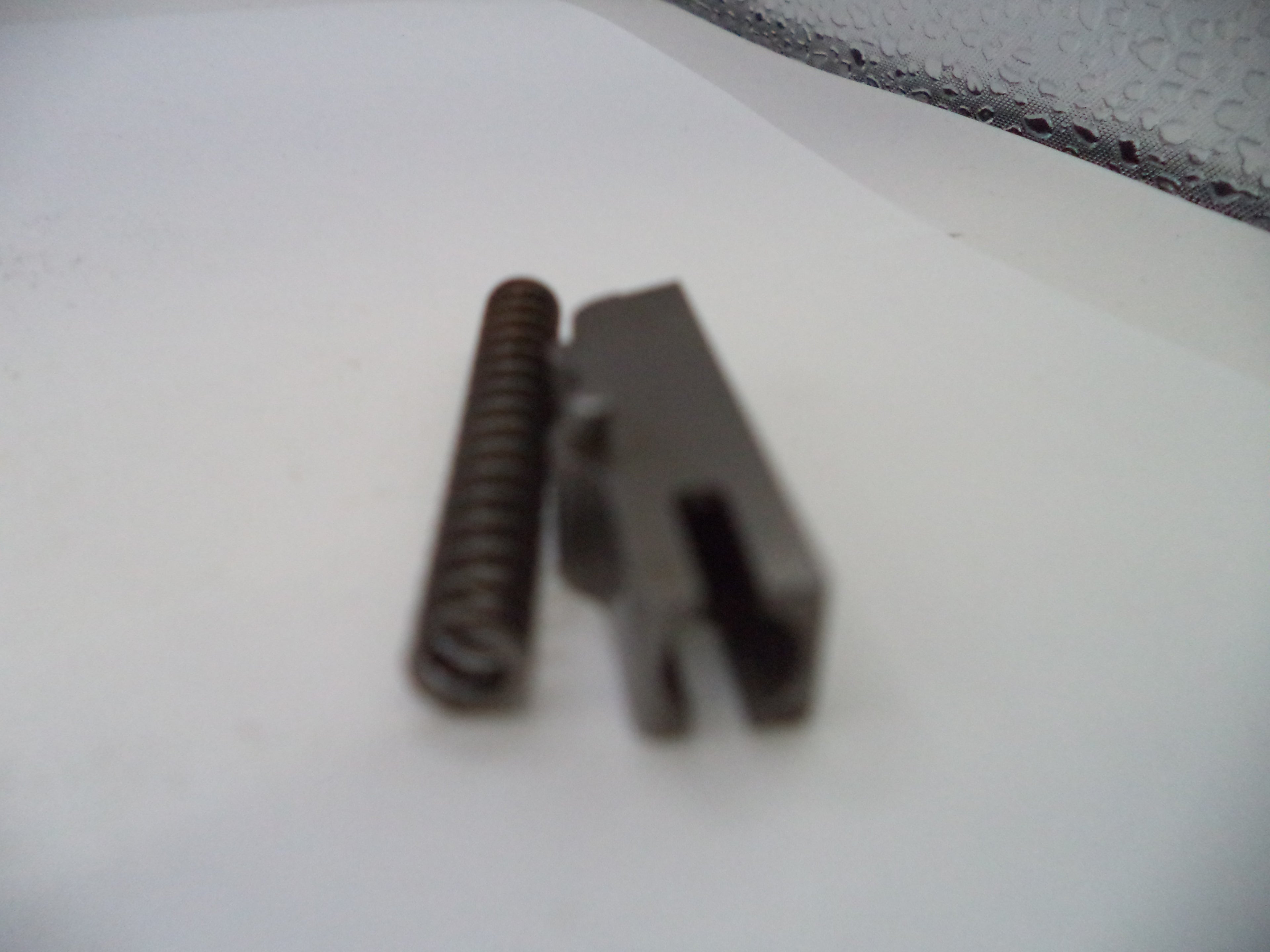 Metal spring and clip on a white surface