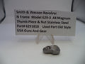 Smith & Wesson revolver thumb piece and nut on a white background with a label.