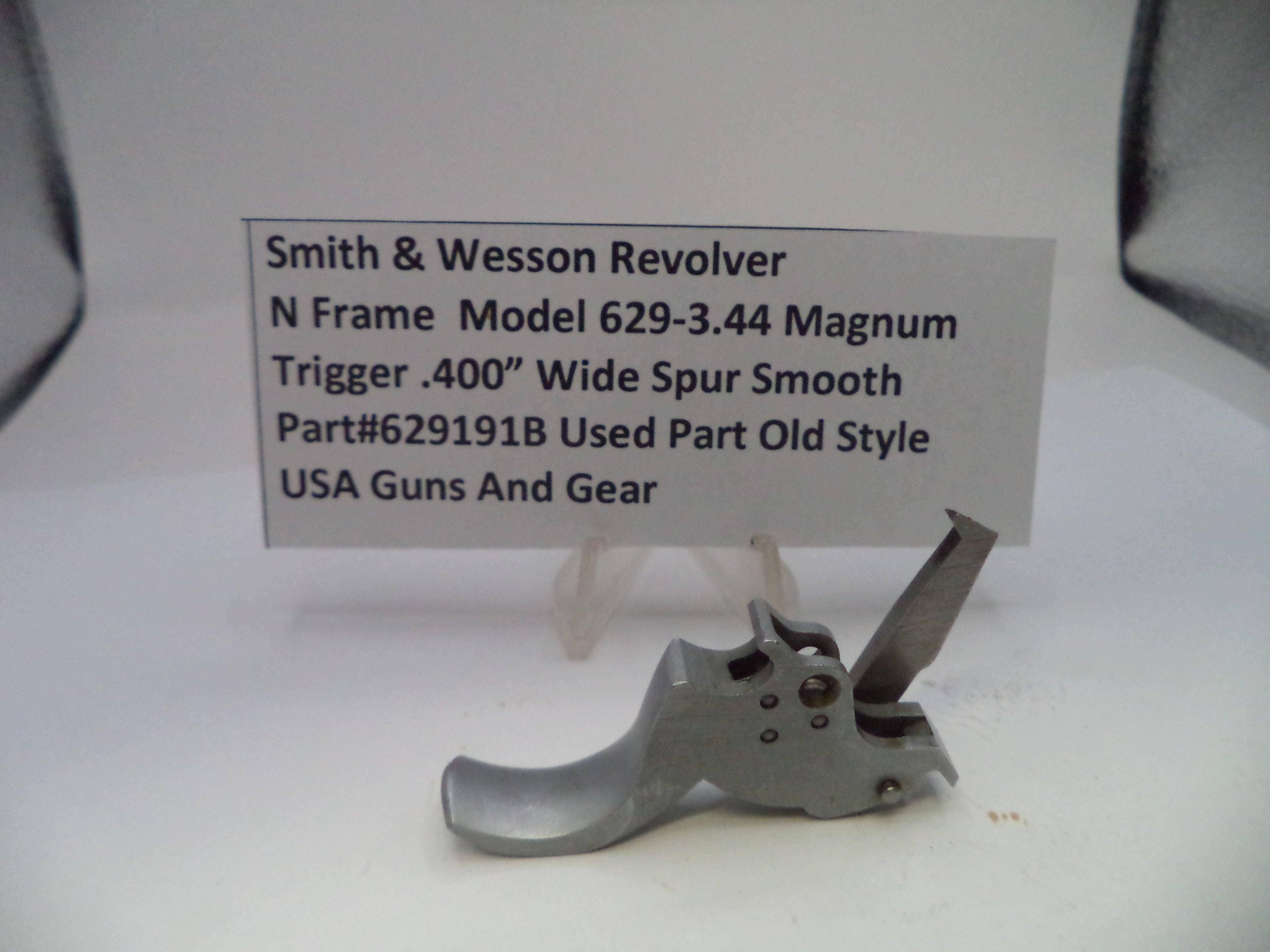 Smith & Wesson revolver trigger part with descriptive card on a white background