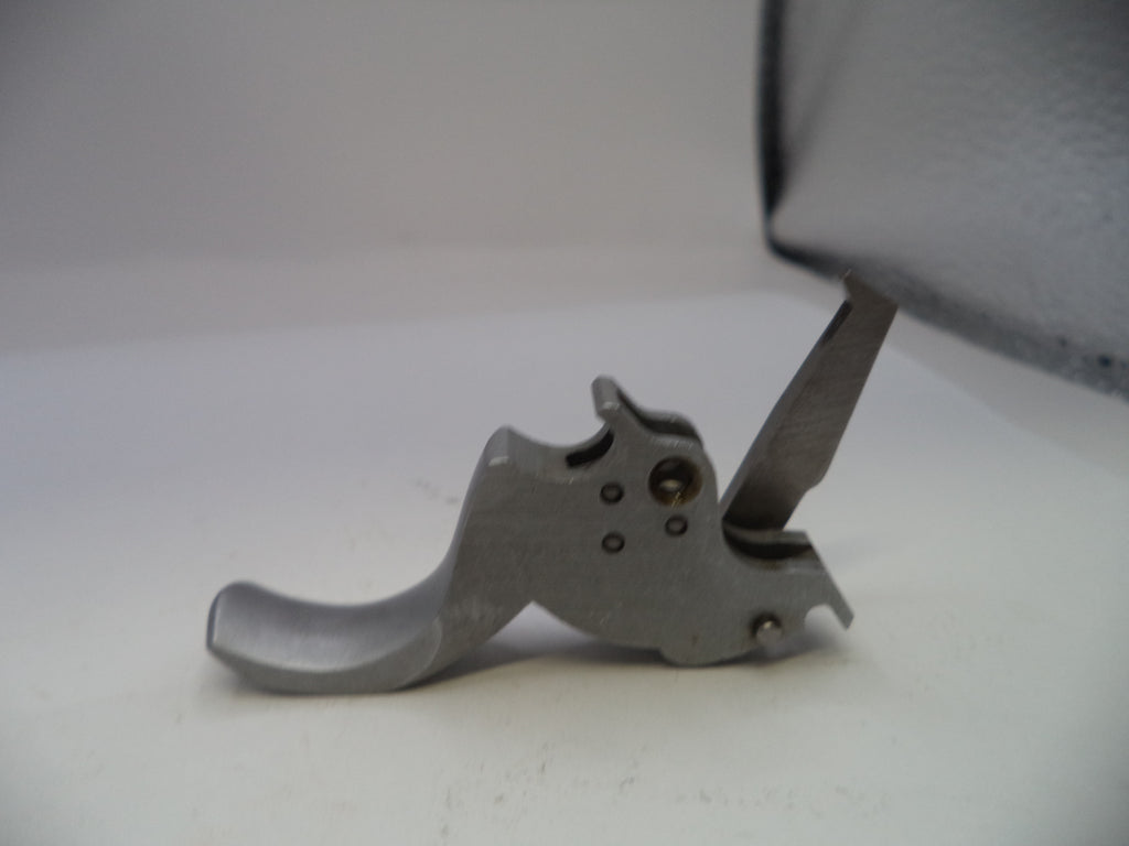 Metallic gun trigger on a white surface with a blurred background