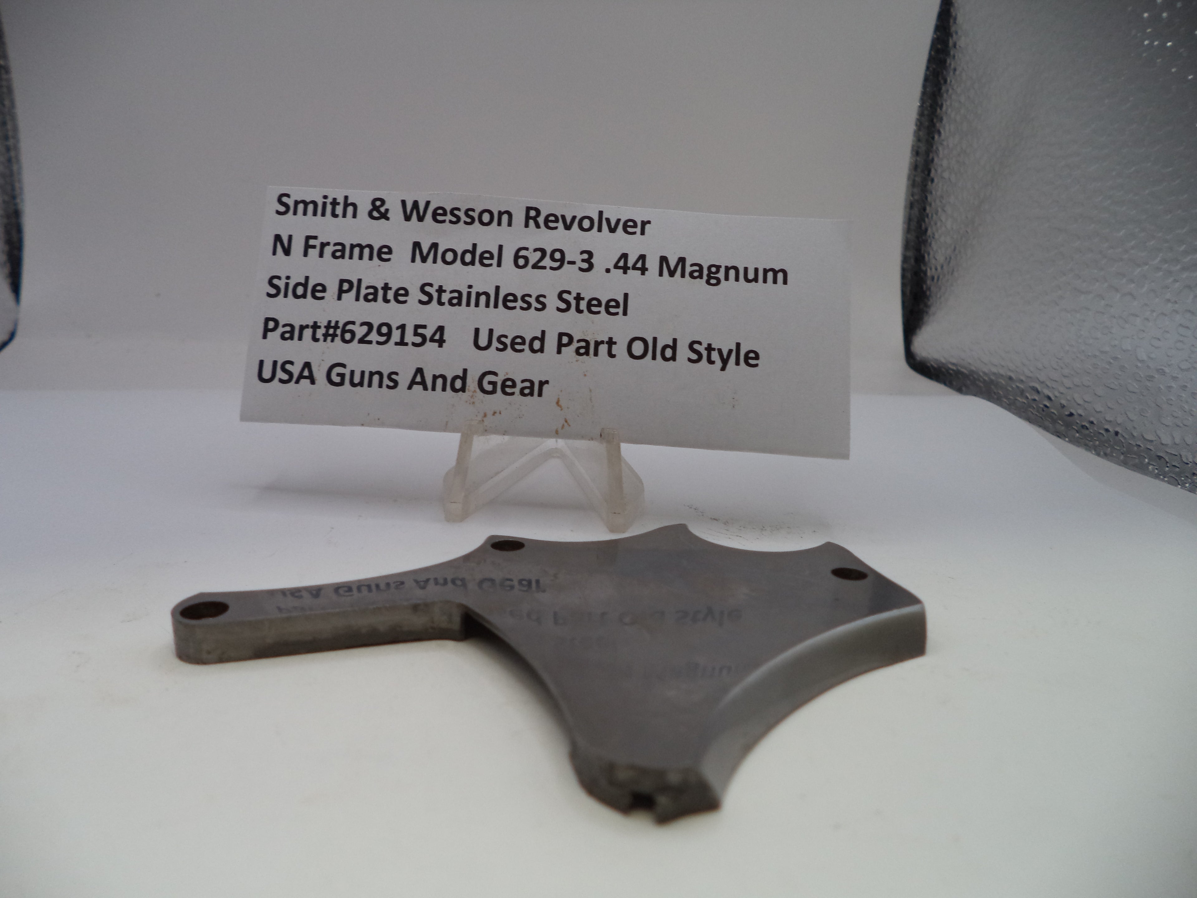 Smith & Wesson revolver side plate on a white background with a label.