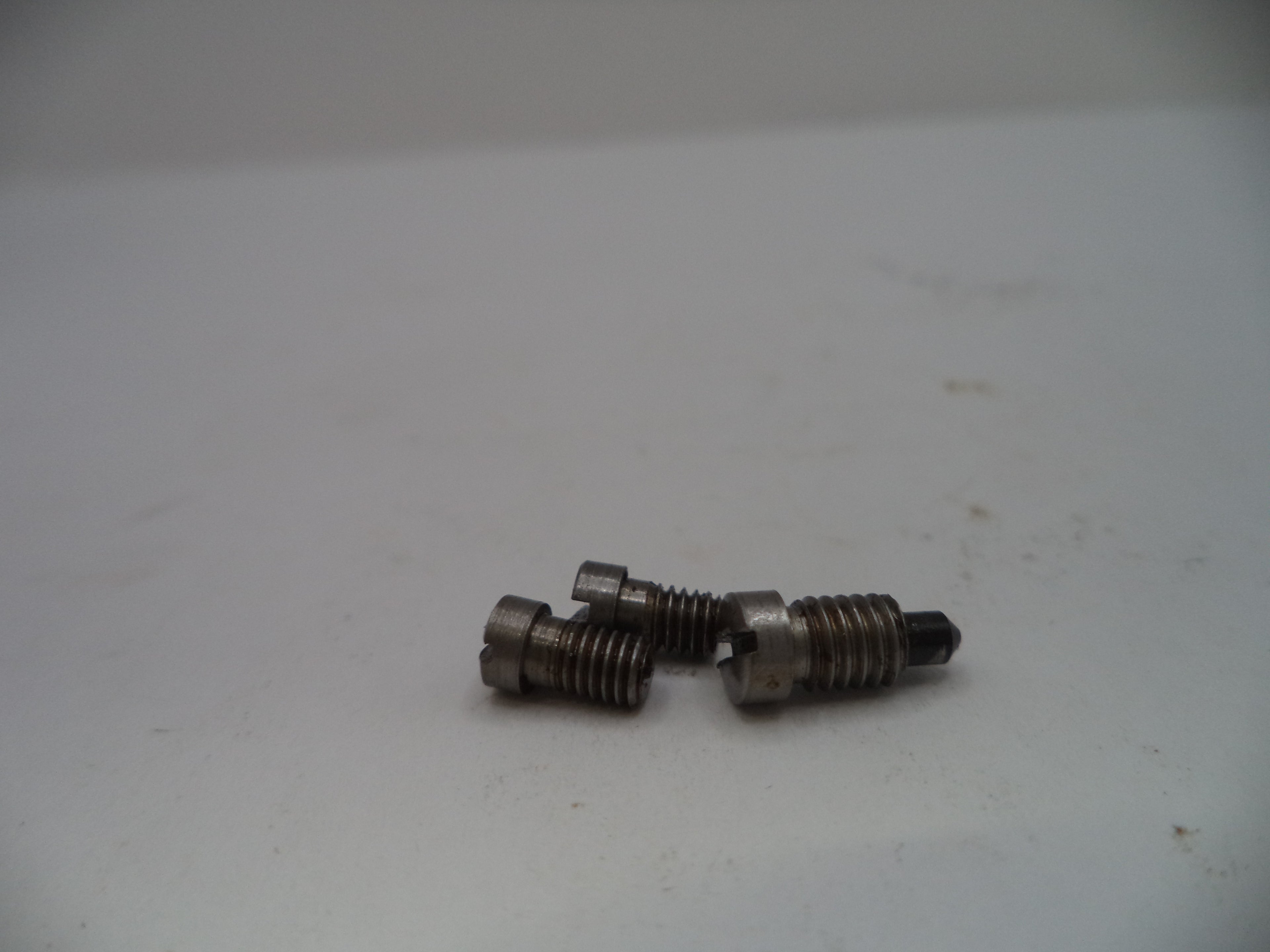 Two small metal screws on a white surface