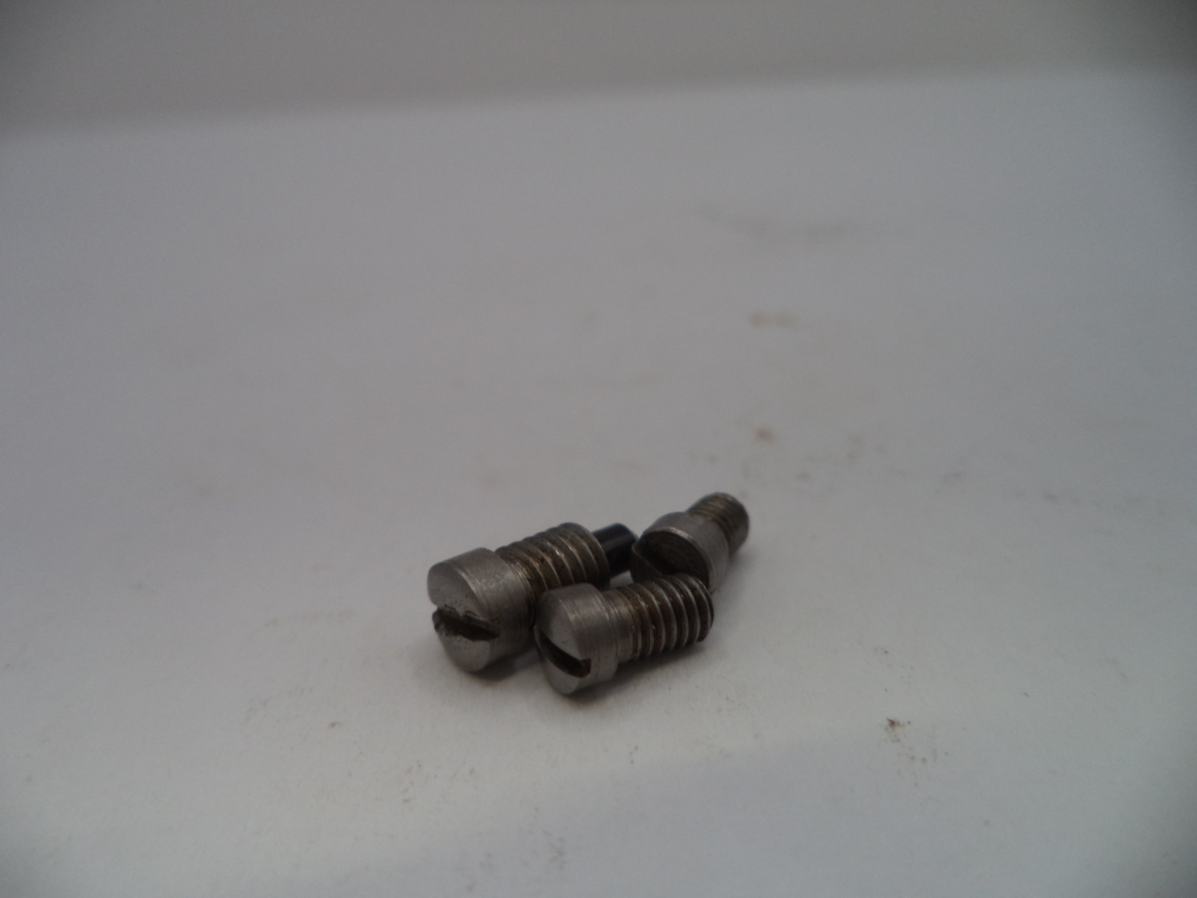 Two metal screws on a white surface