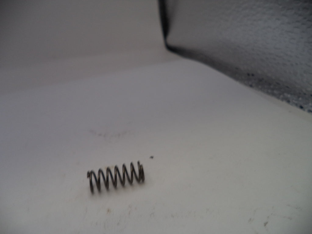 Metal spring on a white surface with a textured gray background