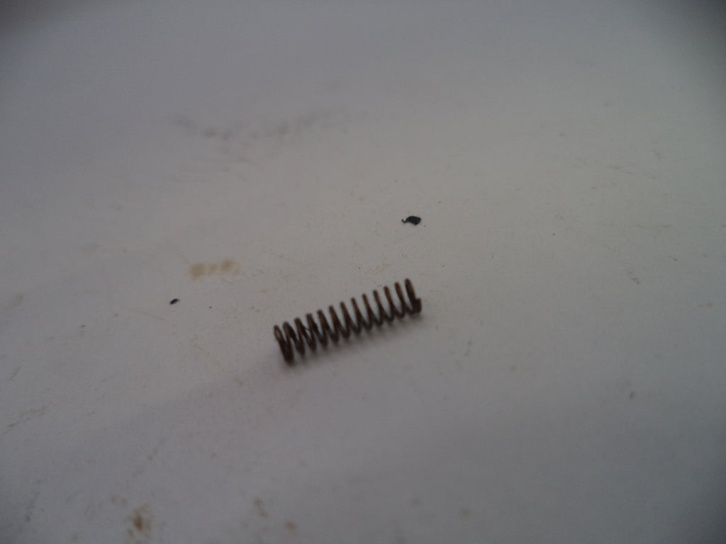Coiled spring on a white surface with visible dirt