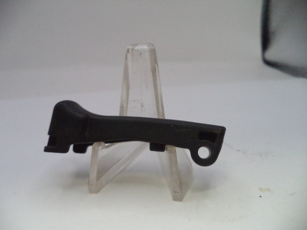 Black plastic component on a clear stand against a white background
