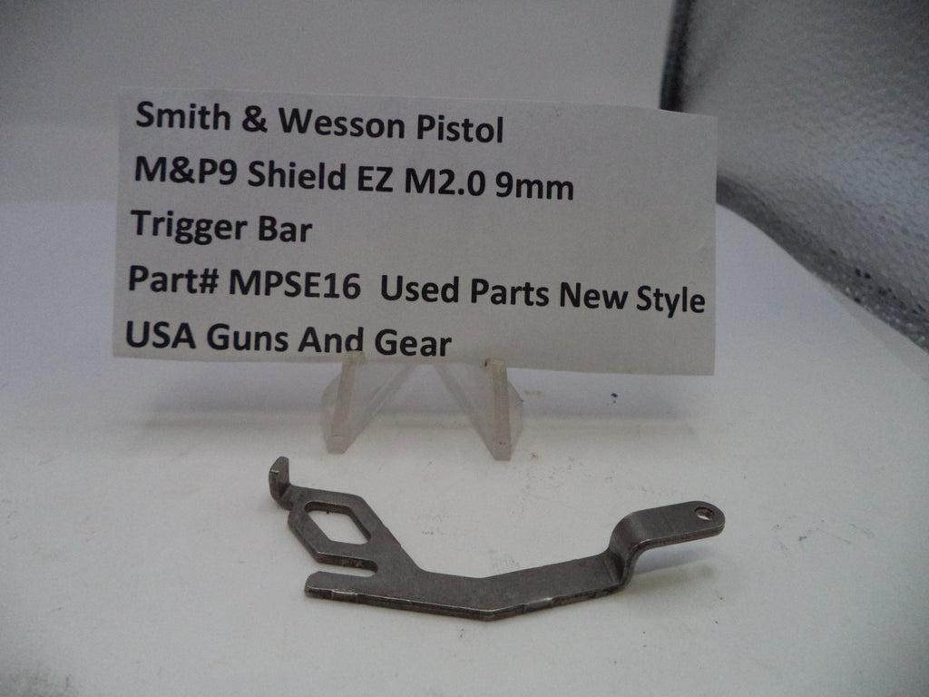 Trigger bar for Smith & Wesson pistol on a white surface with a label.