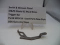 Trigger bar for Smith & Wesson pistol on a white surface with a label.