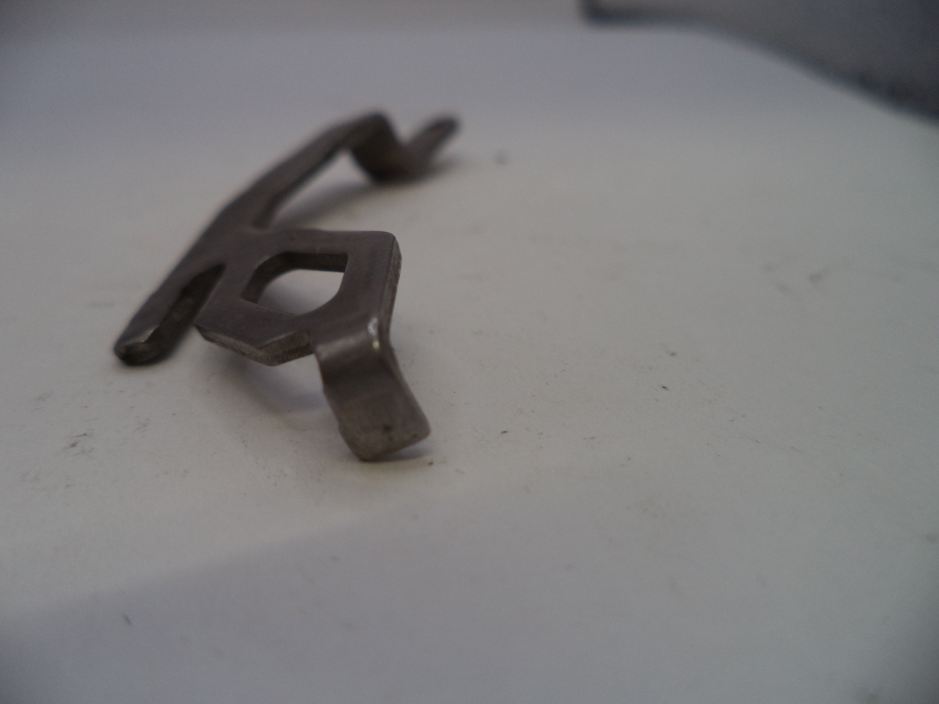 Metallic key-shaped object on a white surface