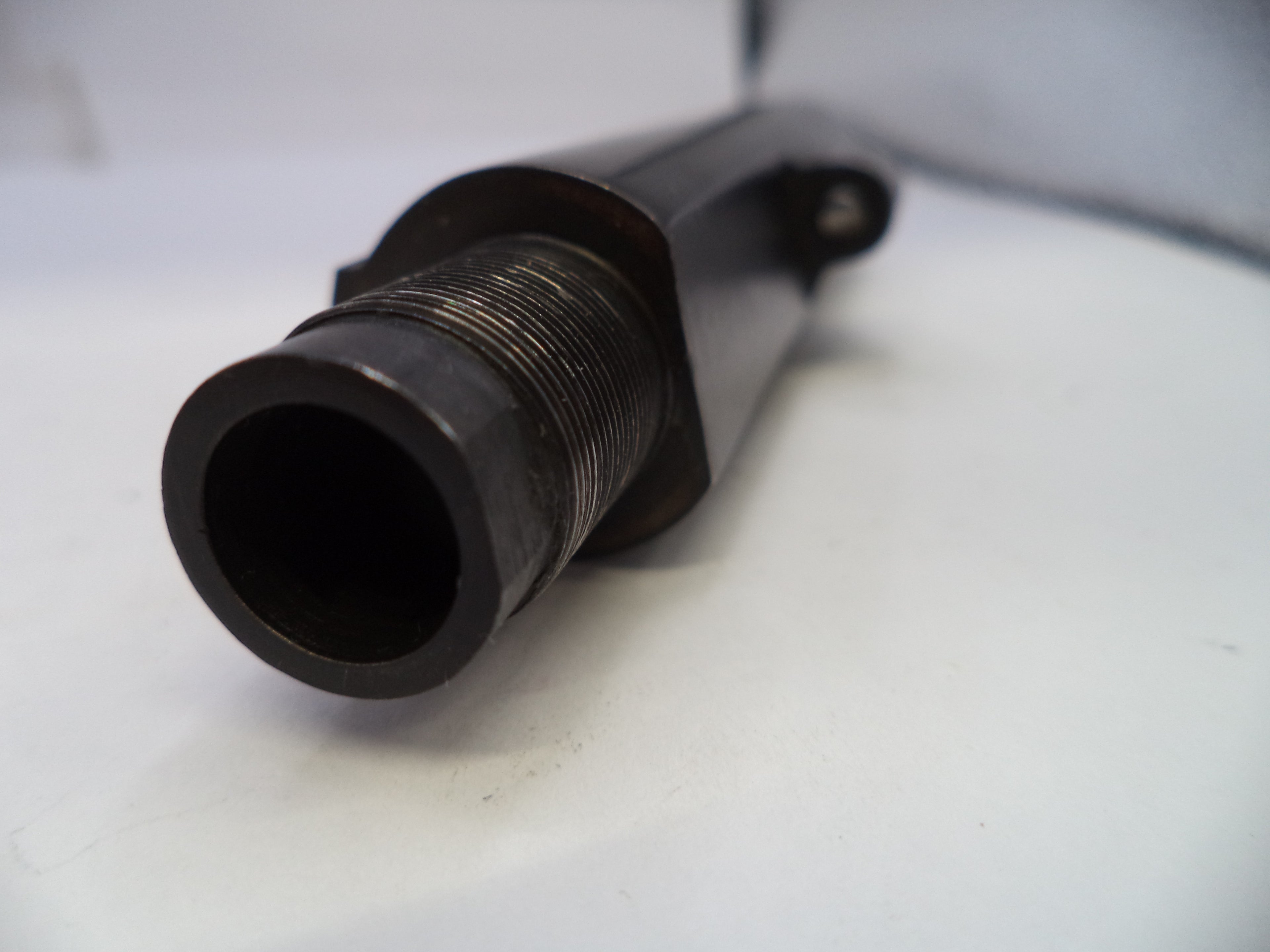 Close-up of a black metal cylindrical object on a white surface