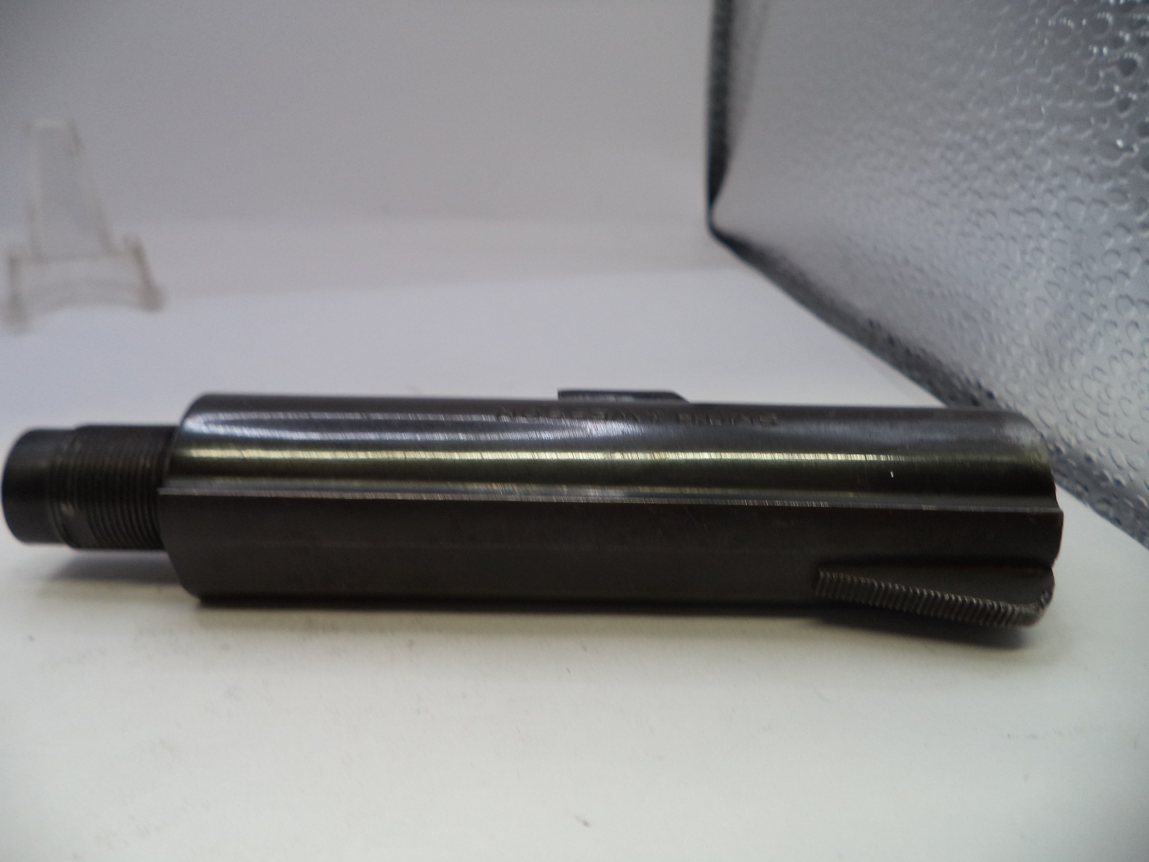 Metal cylindrical object on a white surface with a gray background
