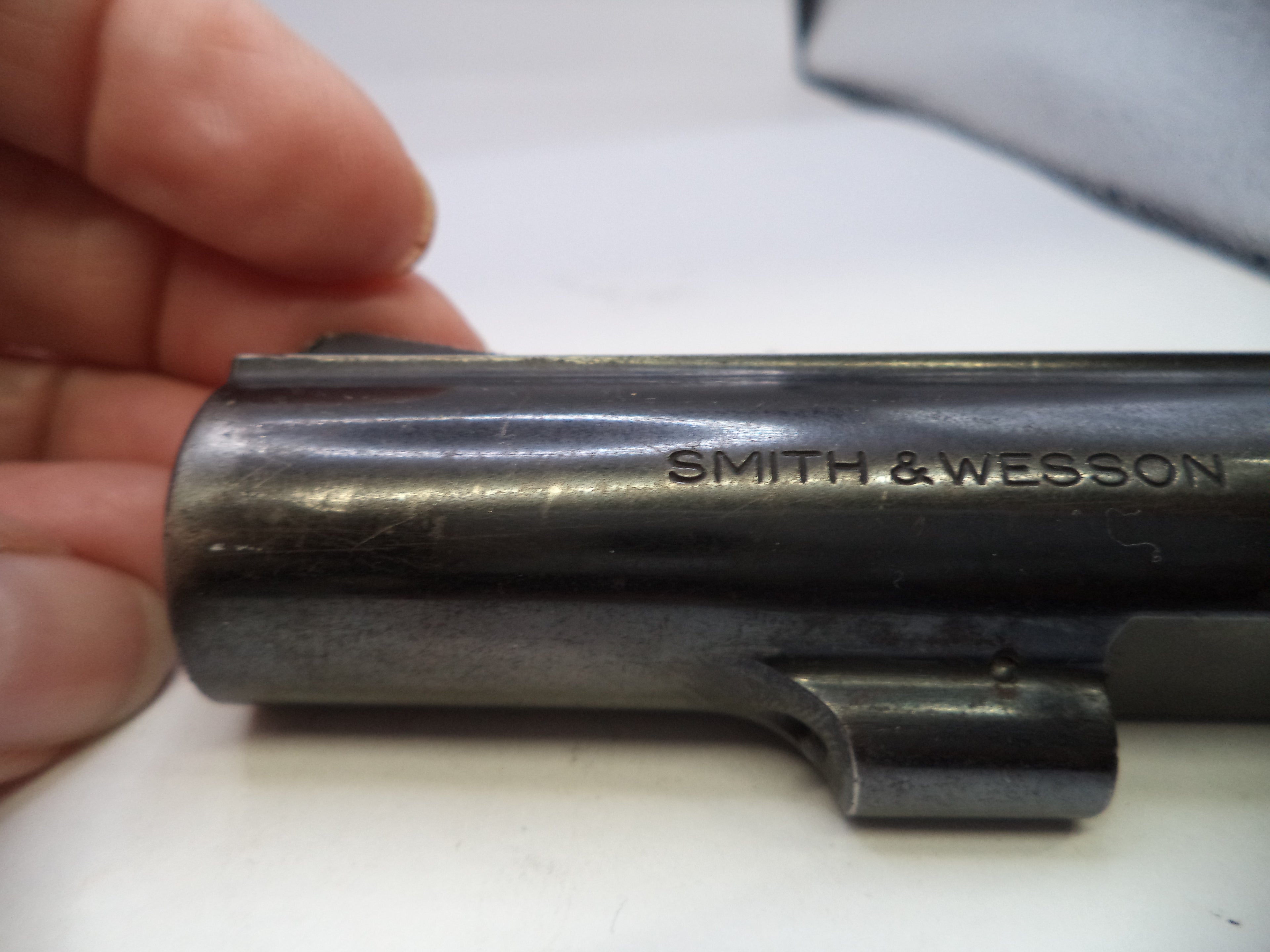 Smith & Wesson gun barrel held by a hand on a white background