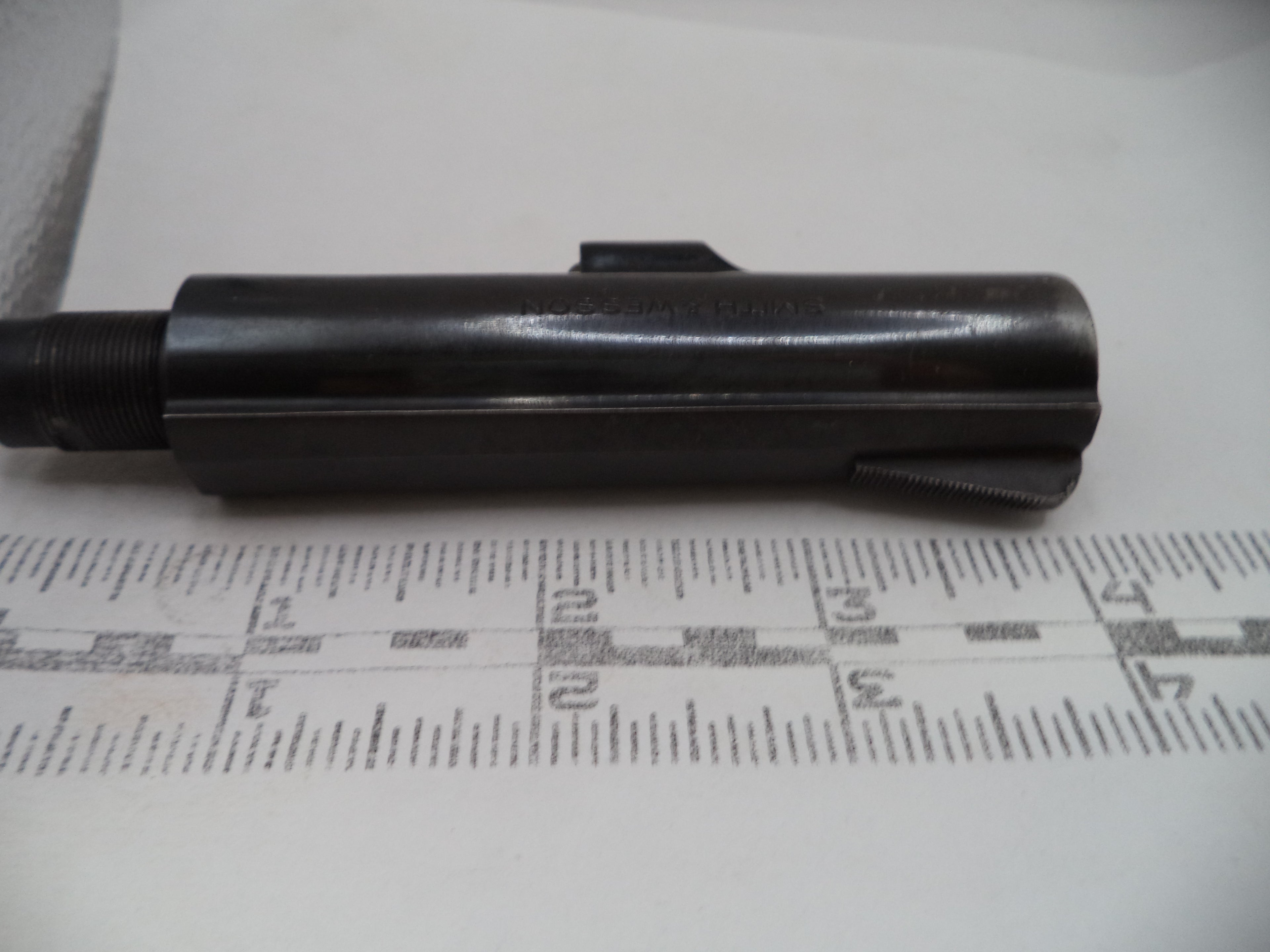 Black cylindrical object on a white surface with measurement markings