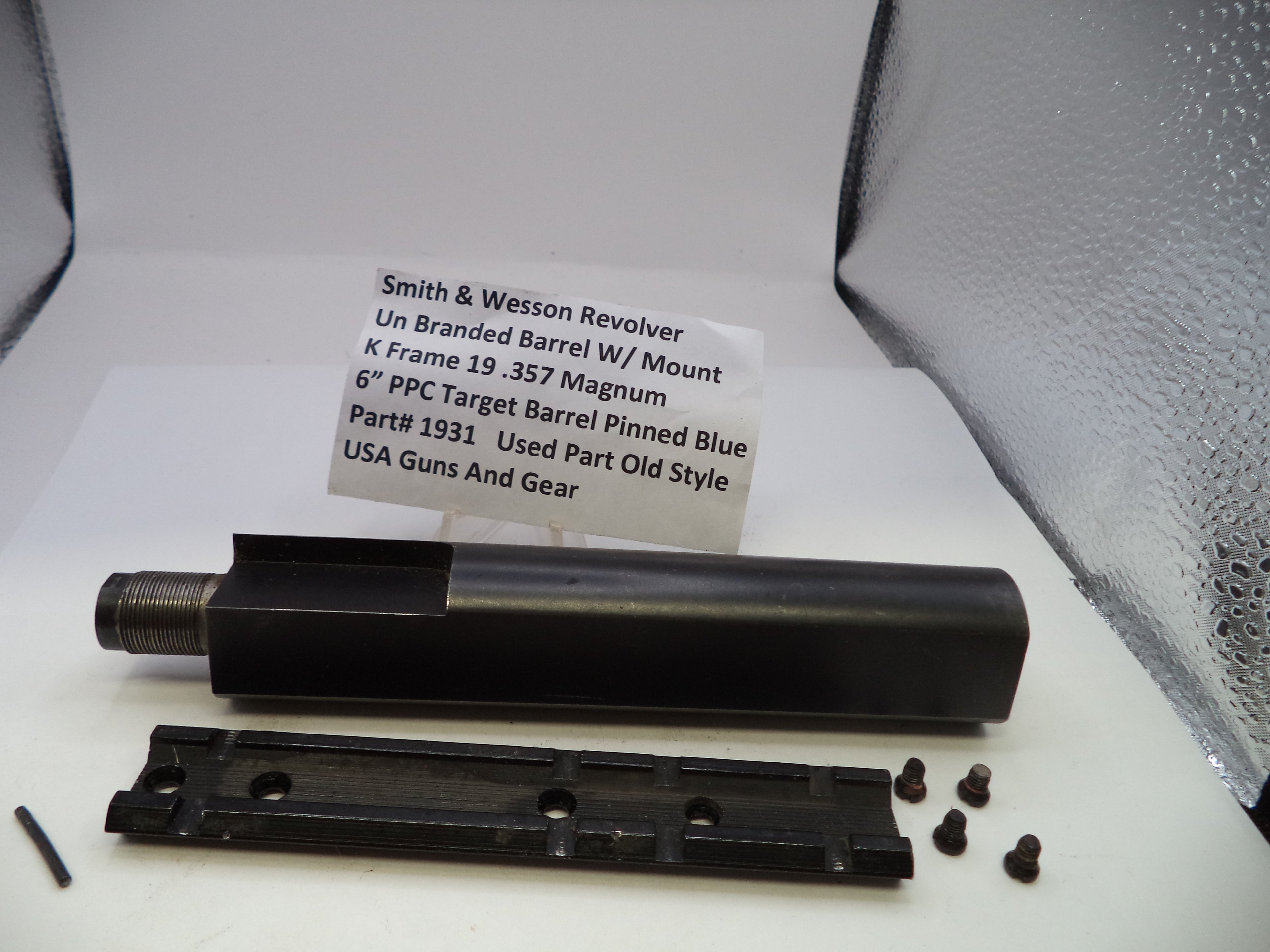 Smith & Wesson revolver barrel and parts on a white surface with a label.