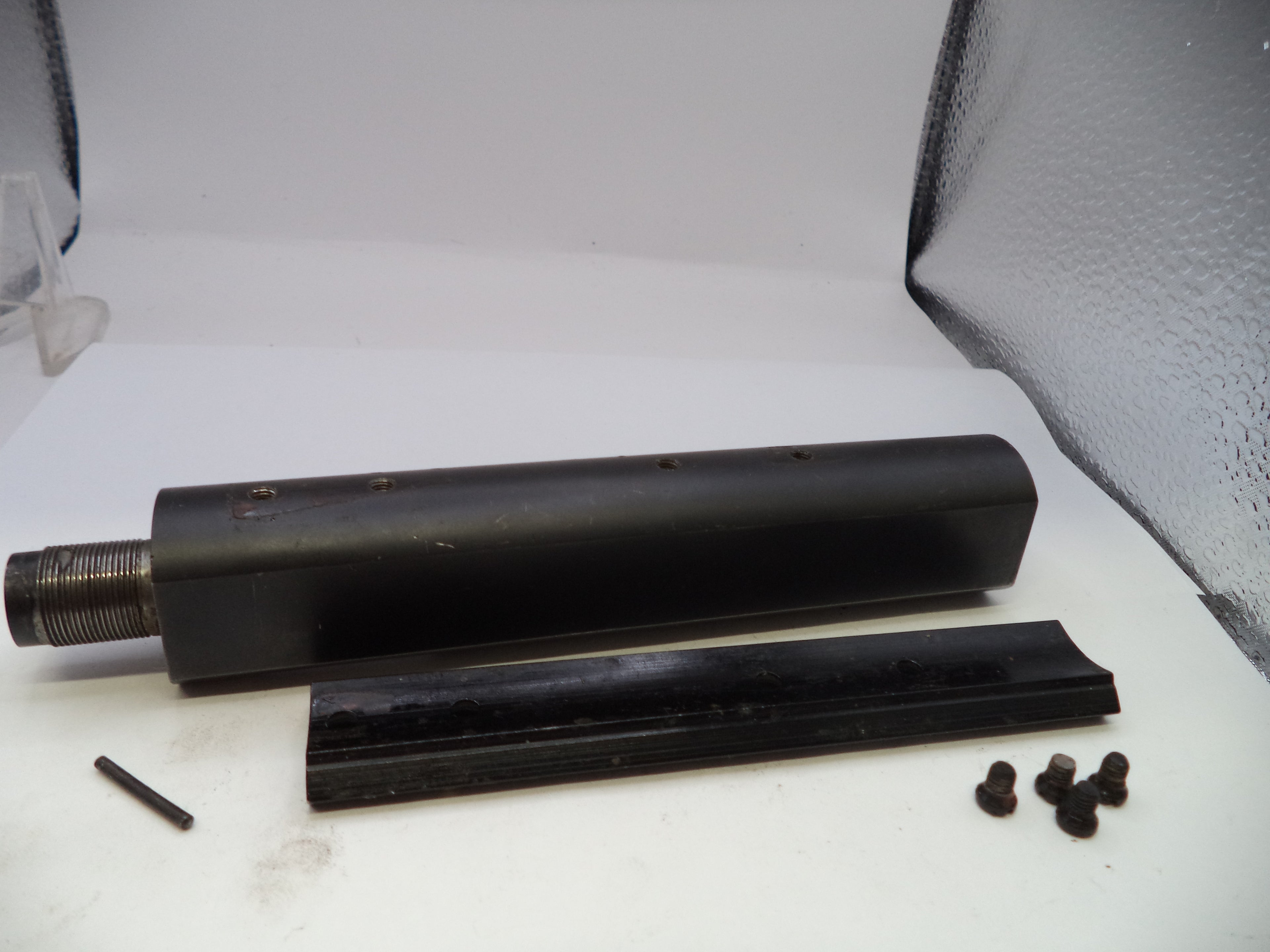 Black metal component with smaller parts on a white surface