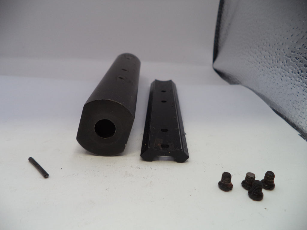 Black cylindrical and rectangular metal components with small black bolts on a white surface.