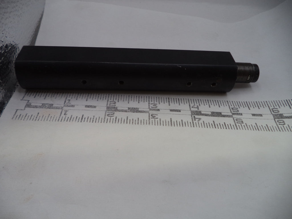 Black cylindrical object on a white surface with a ruler for scale.