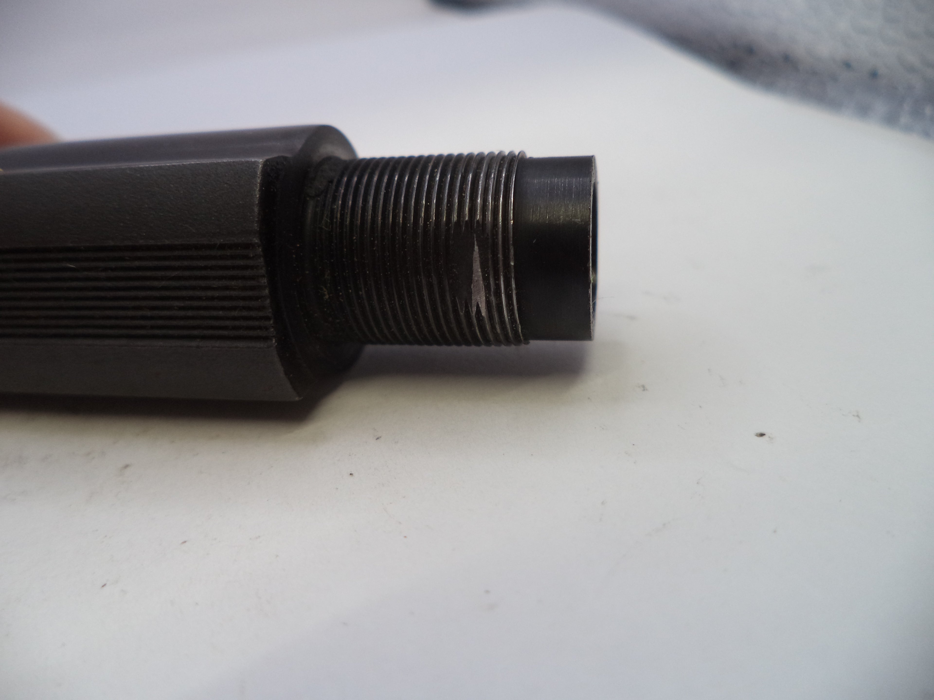 Black threaded cylindrical object on a white surface
