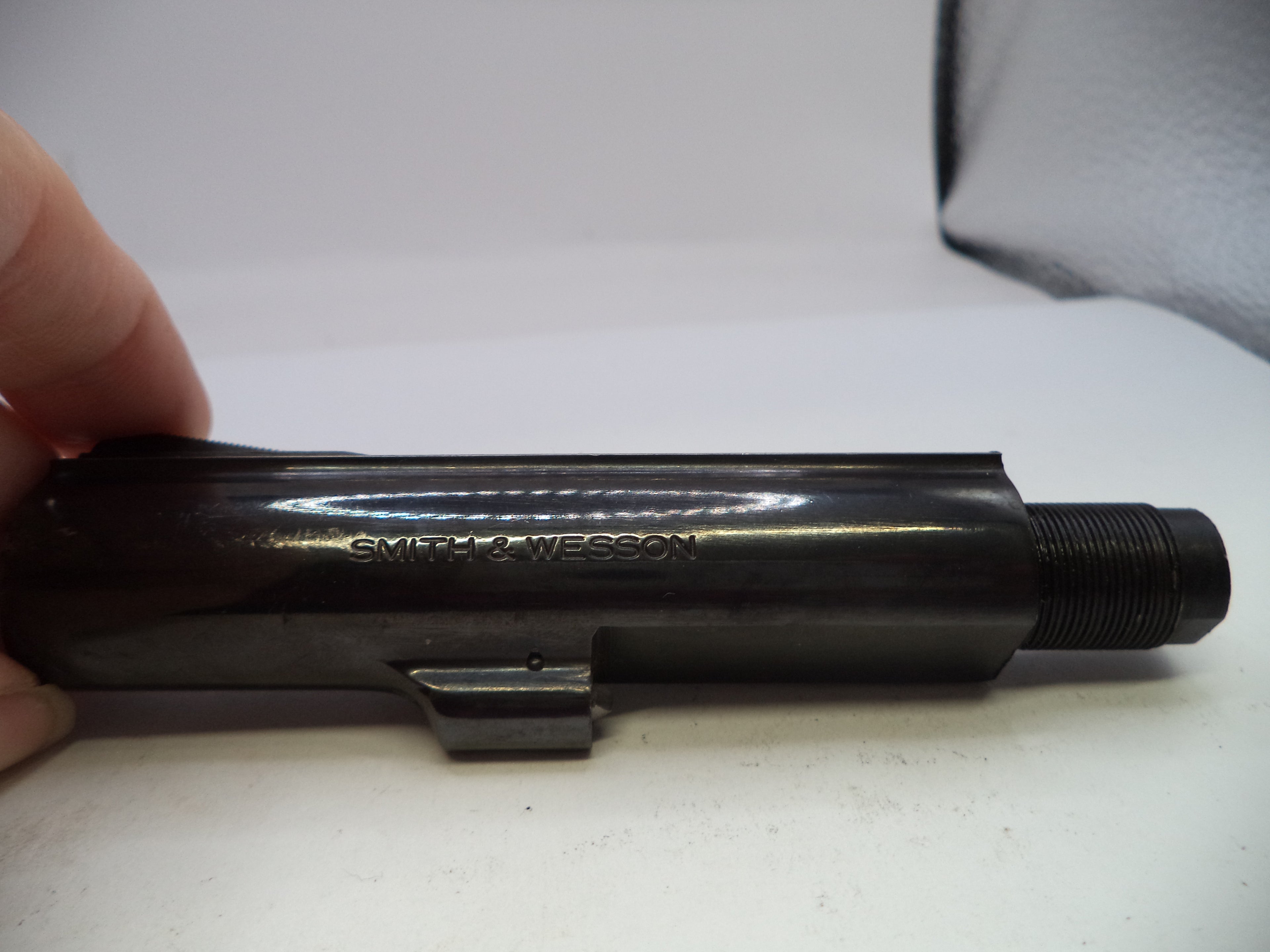 Black firearm barrel with 'Smith & Wesson' branding on a white surface.