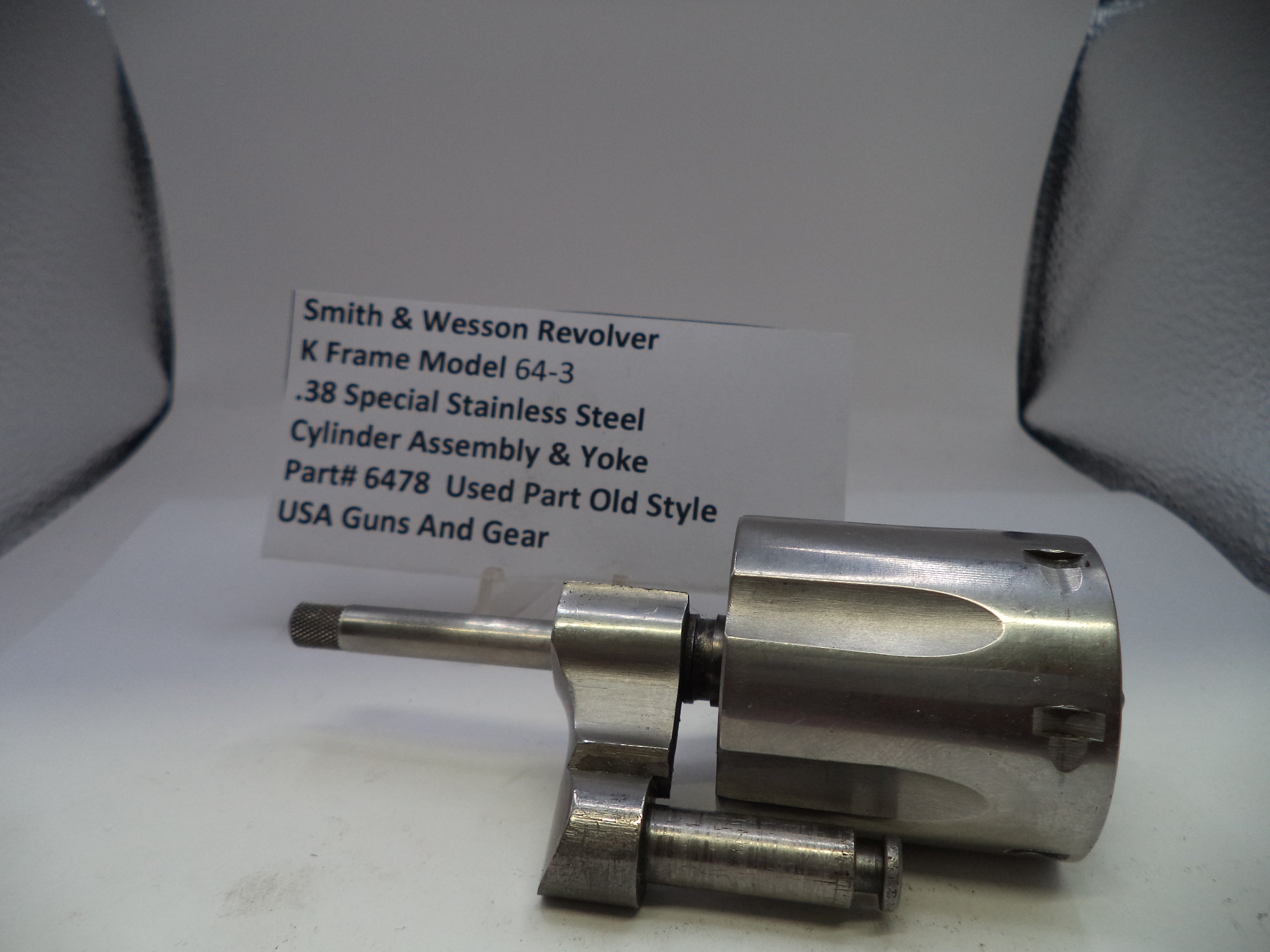 Smith & Wesson revolver cylinder assembly on a white surface with a label in the background.