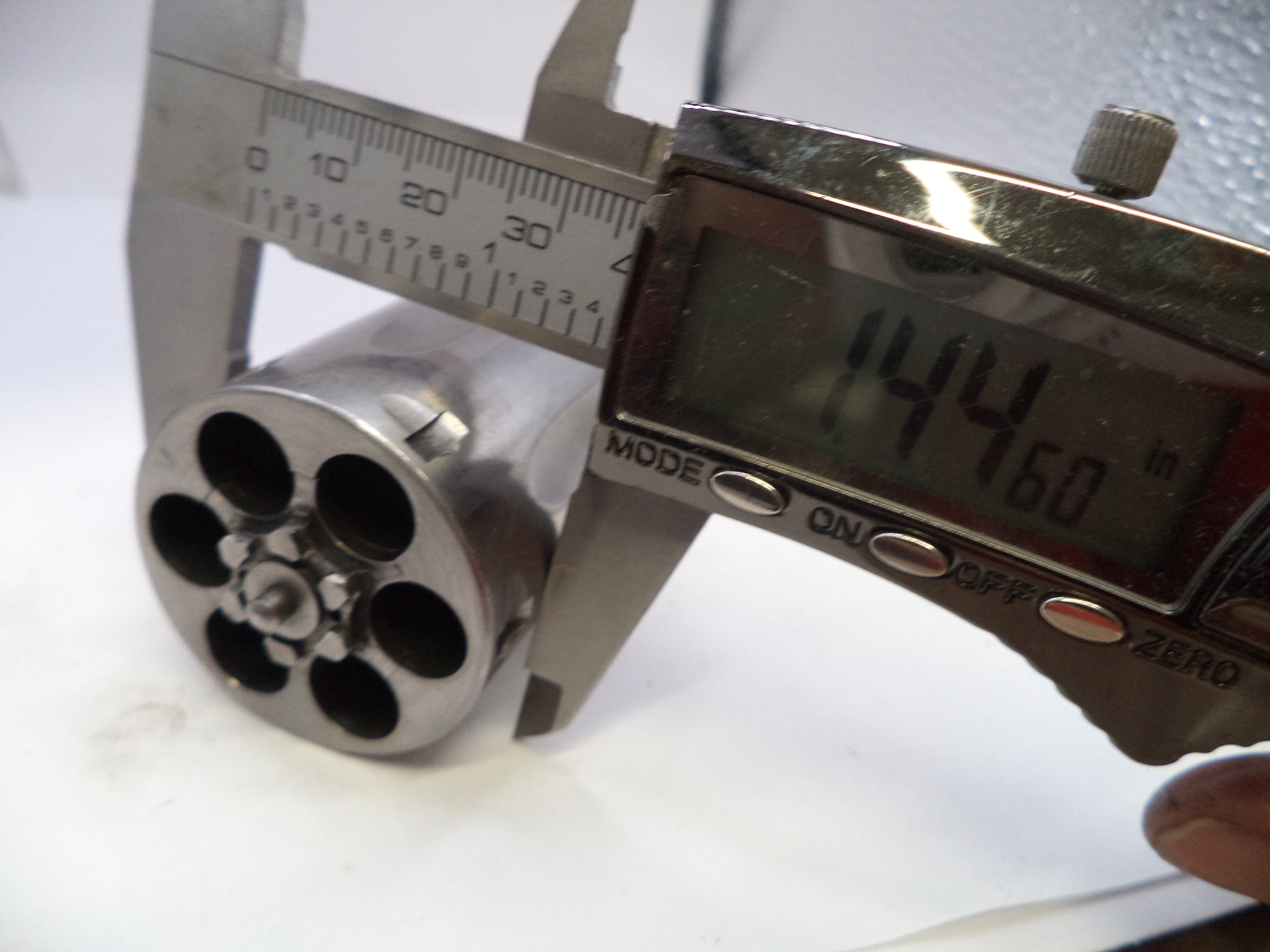 Digital caliper measuring a cylindrical metal object with a white background