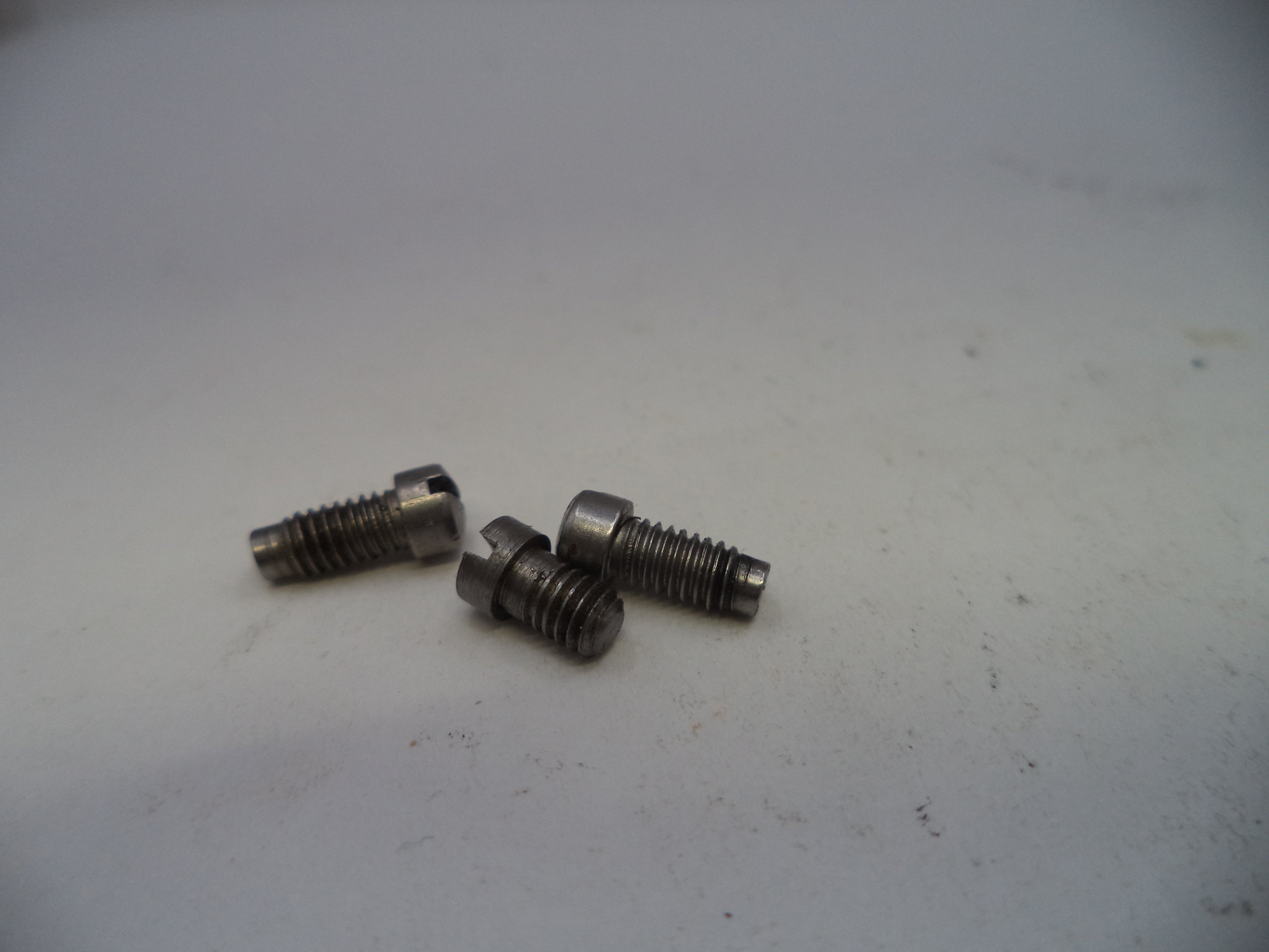 Three metal screws on a white surface