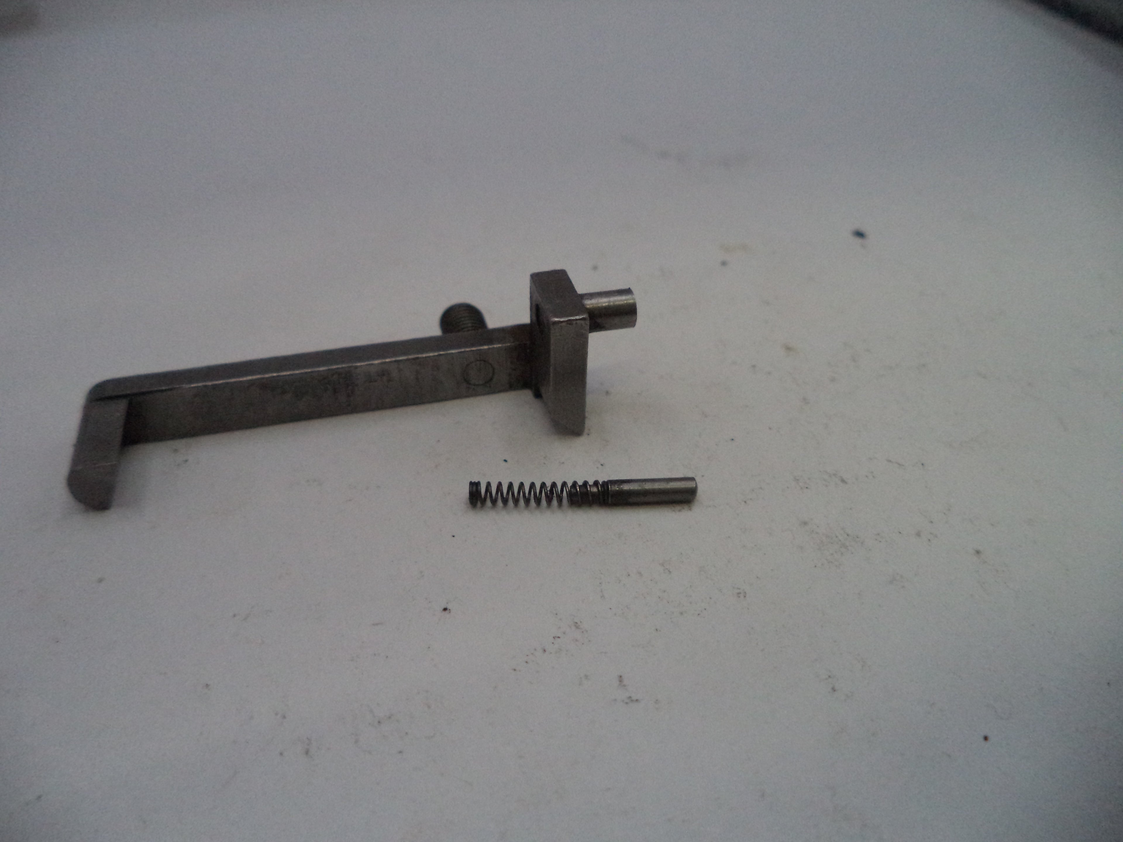 Metal tool and spring on a white surface