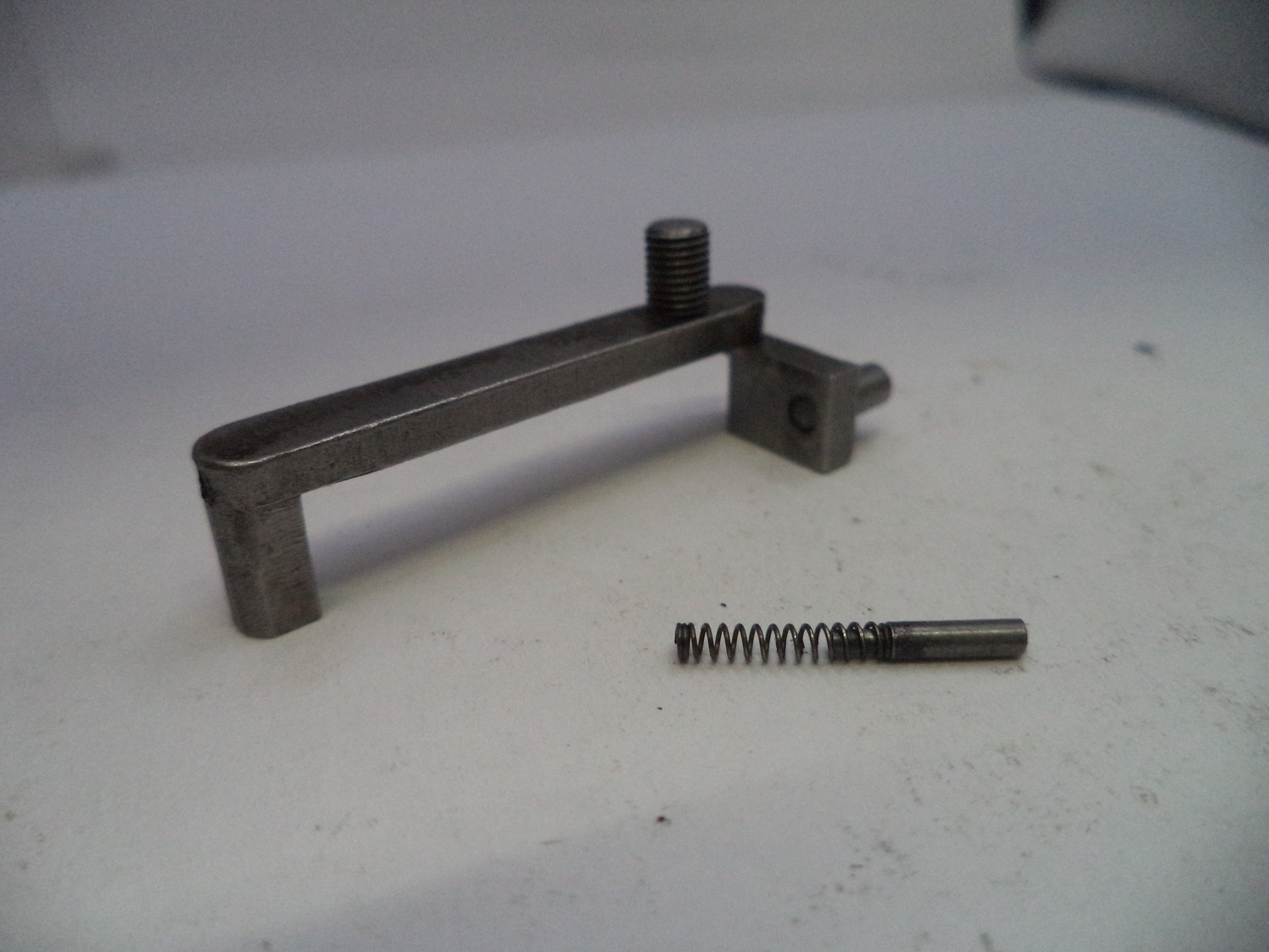 Metal tool and spring on a white surface