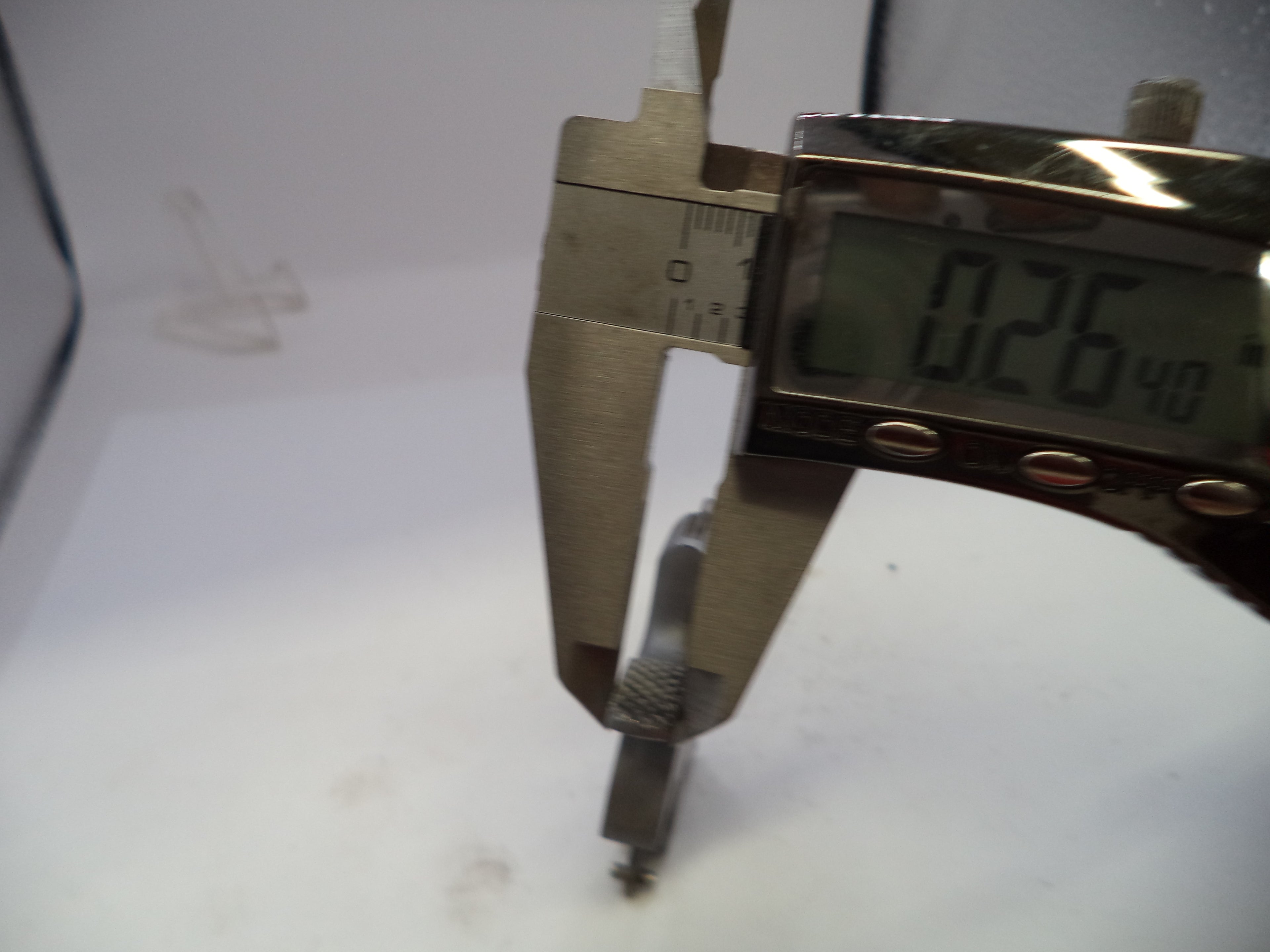 Digital caliper measuring a small object on a white background