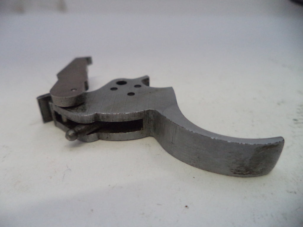 Metallic firearm part on a white surface