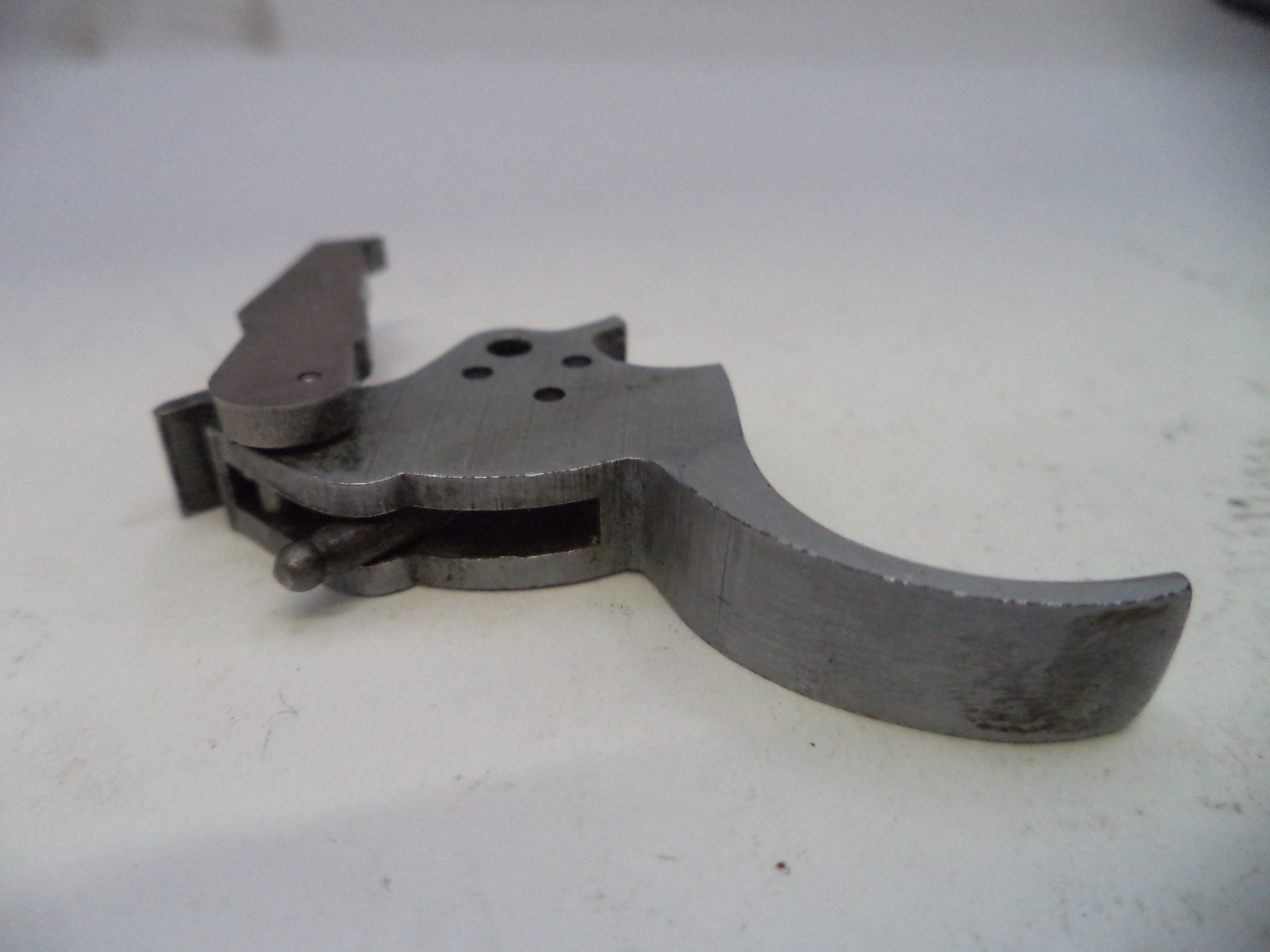 Metallic firearm part on a white surface