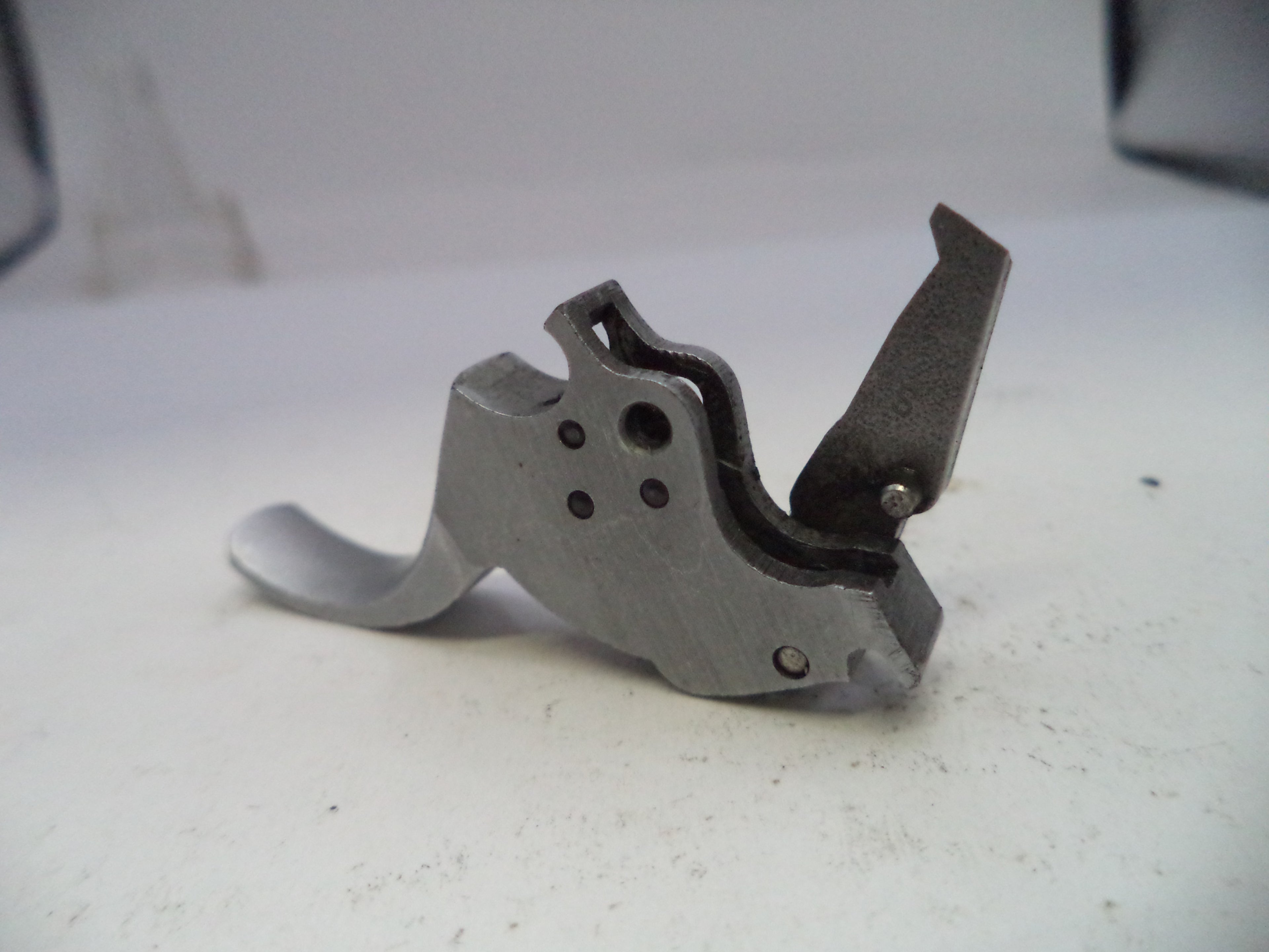 Metal gun trigger on a white surface