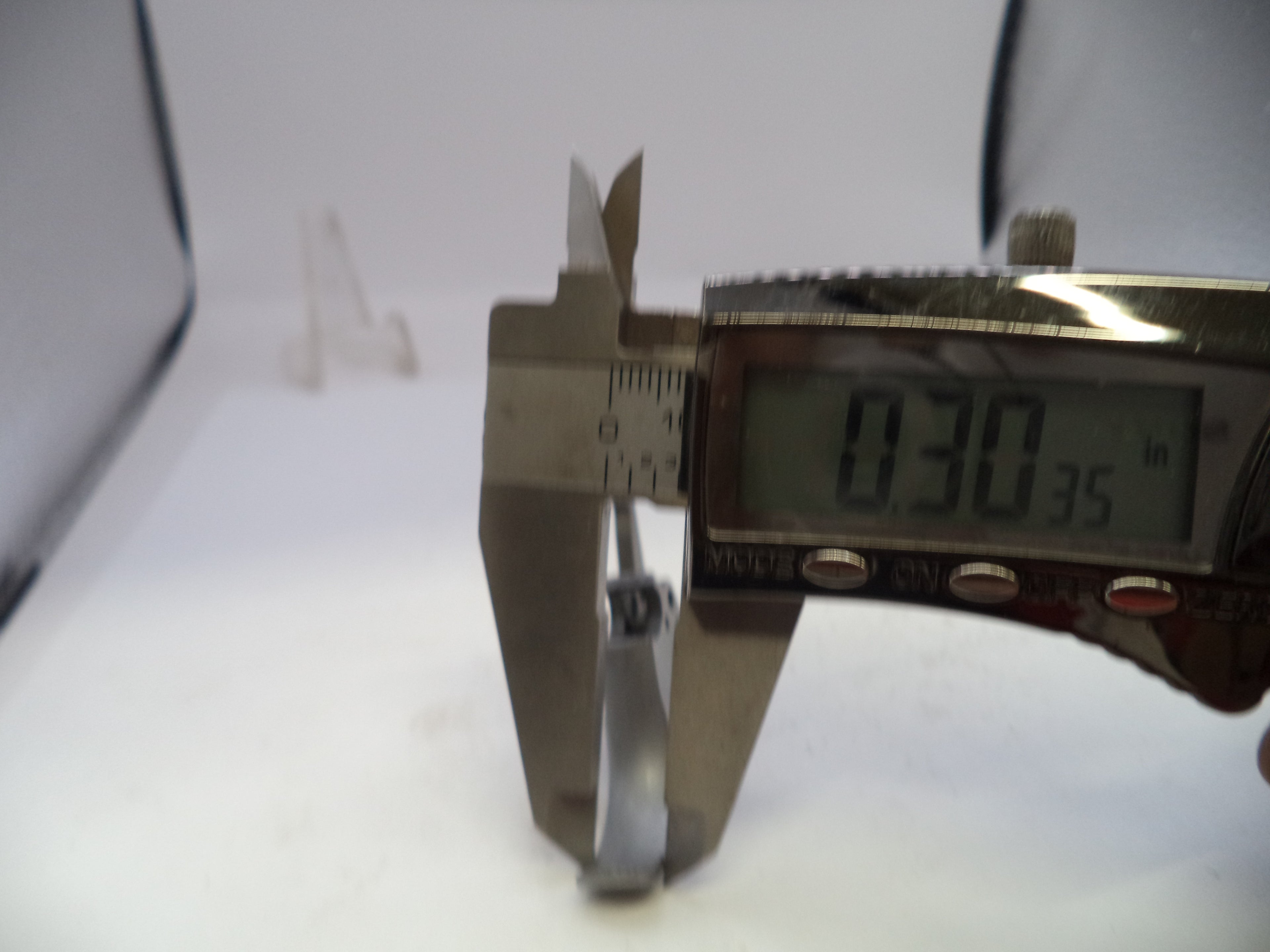 Digital caliper measuring a small object with a white background