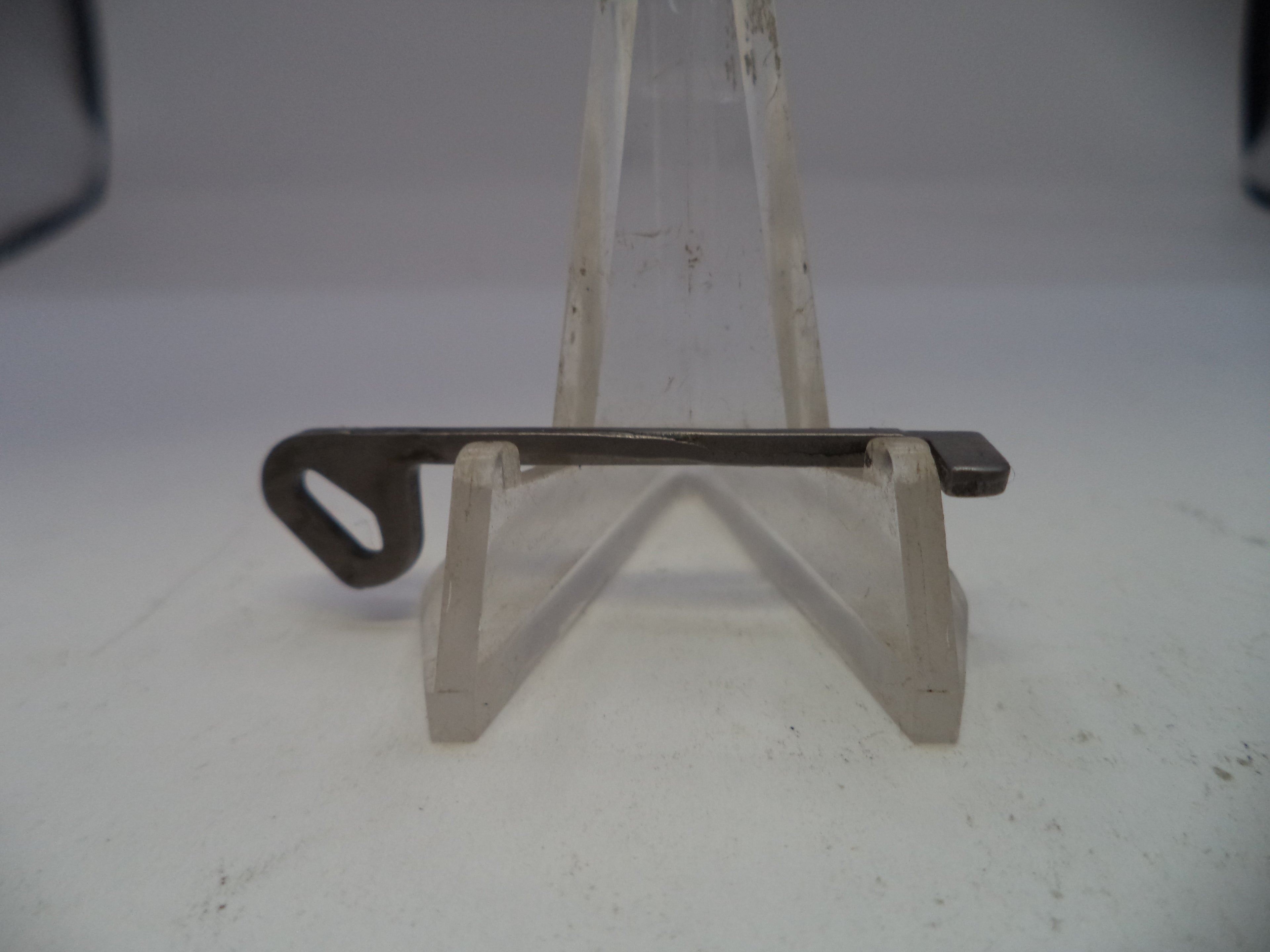 Metal bracket on a clear plastic stand against a white background