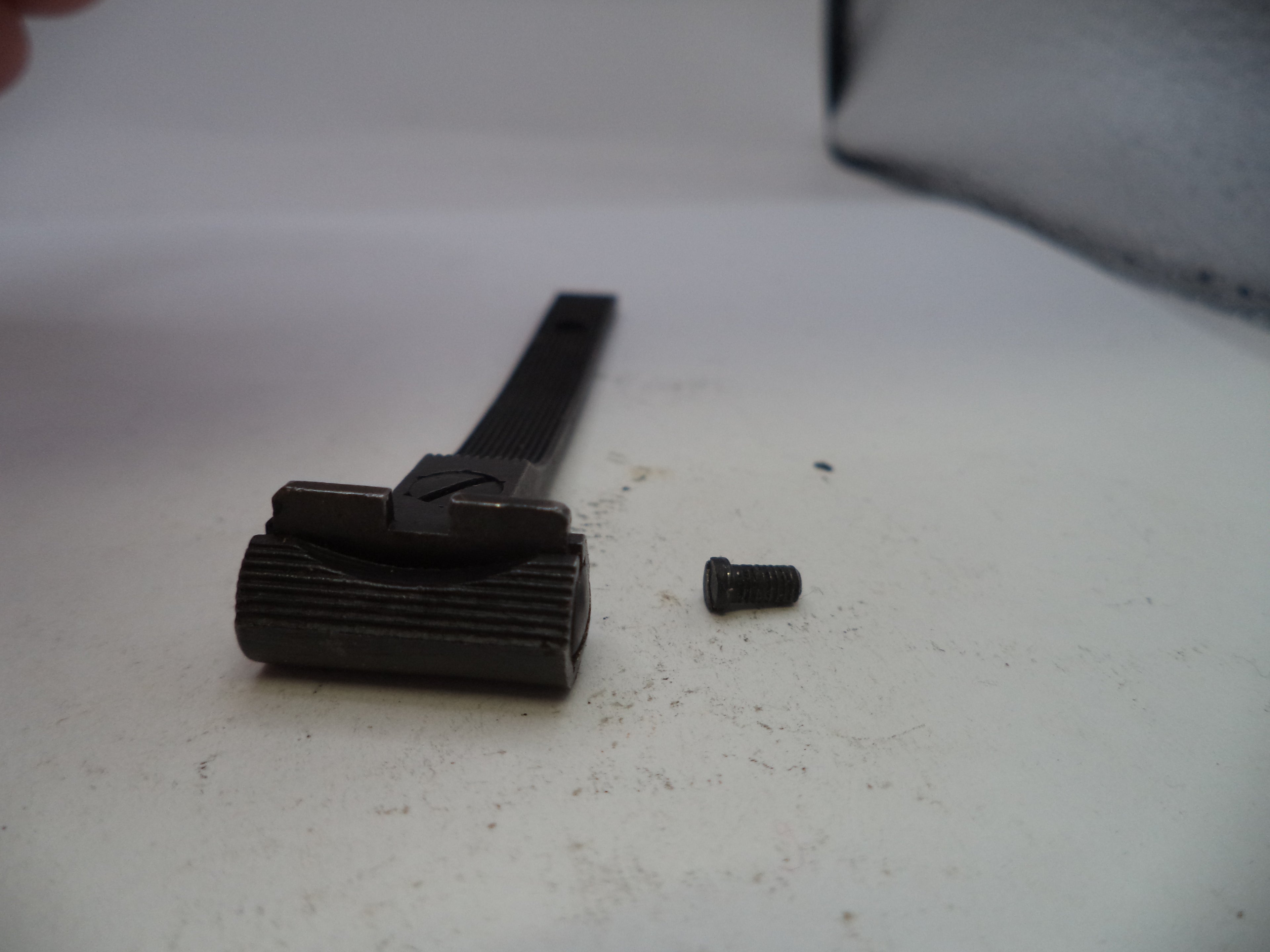 Black metal component and screw on a white surface