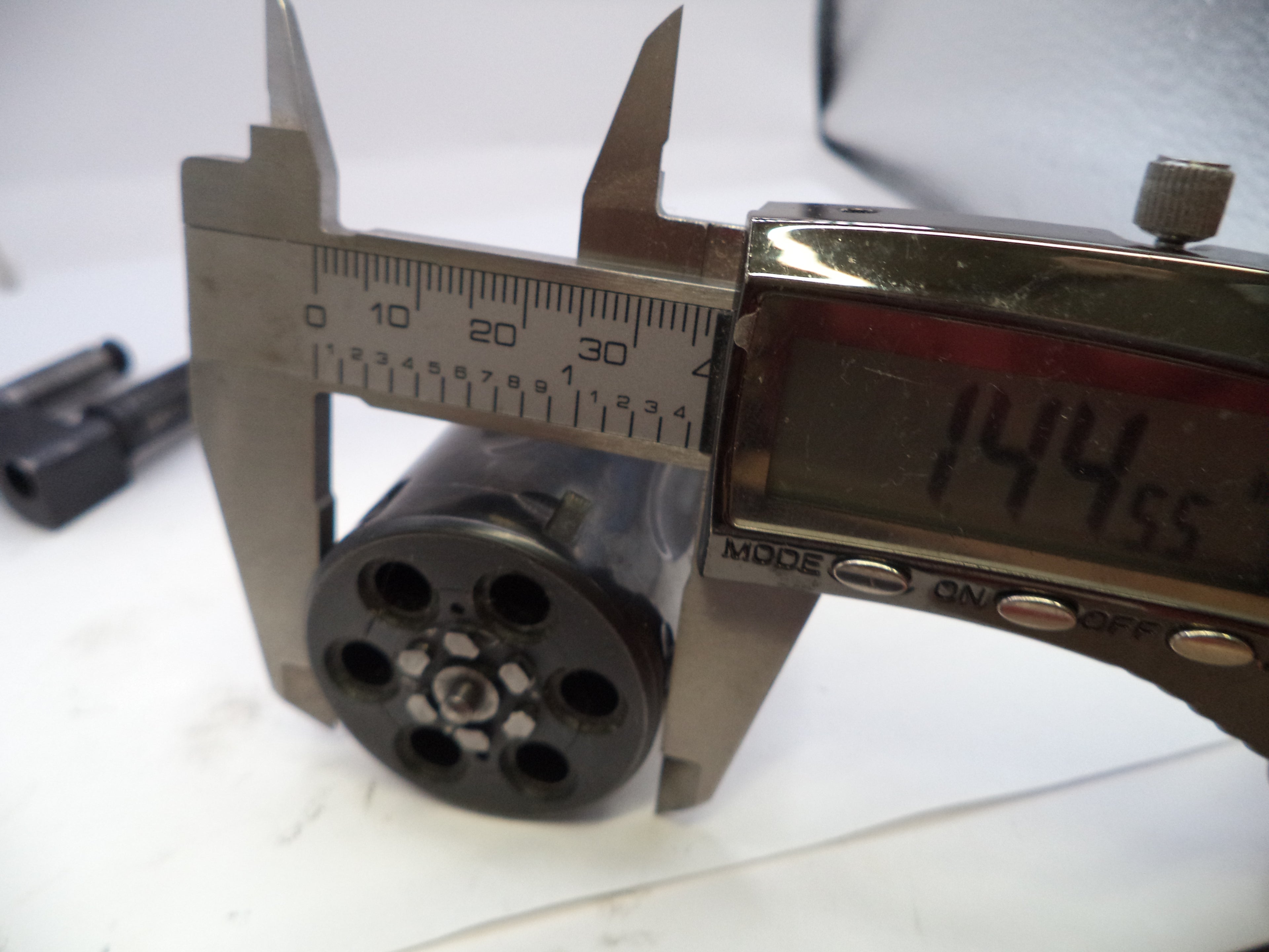 Caliper measuring a cylindrical object with a digital display showing measurement.